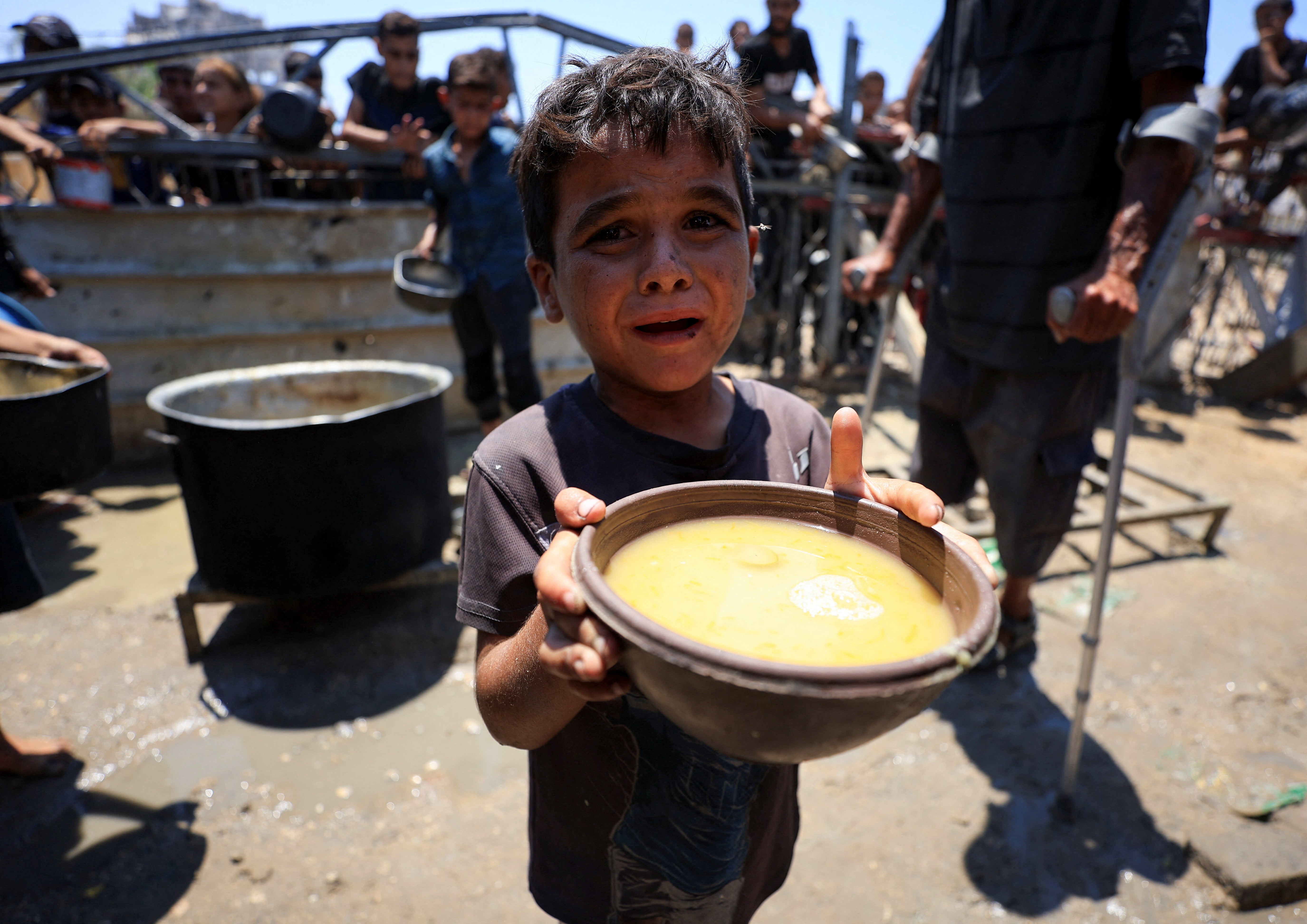 A Palestinians child holds a bowl with food received from a charity kitchen, amid a hunger crisis, in Gaza