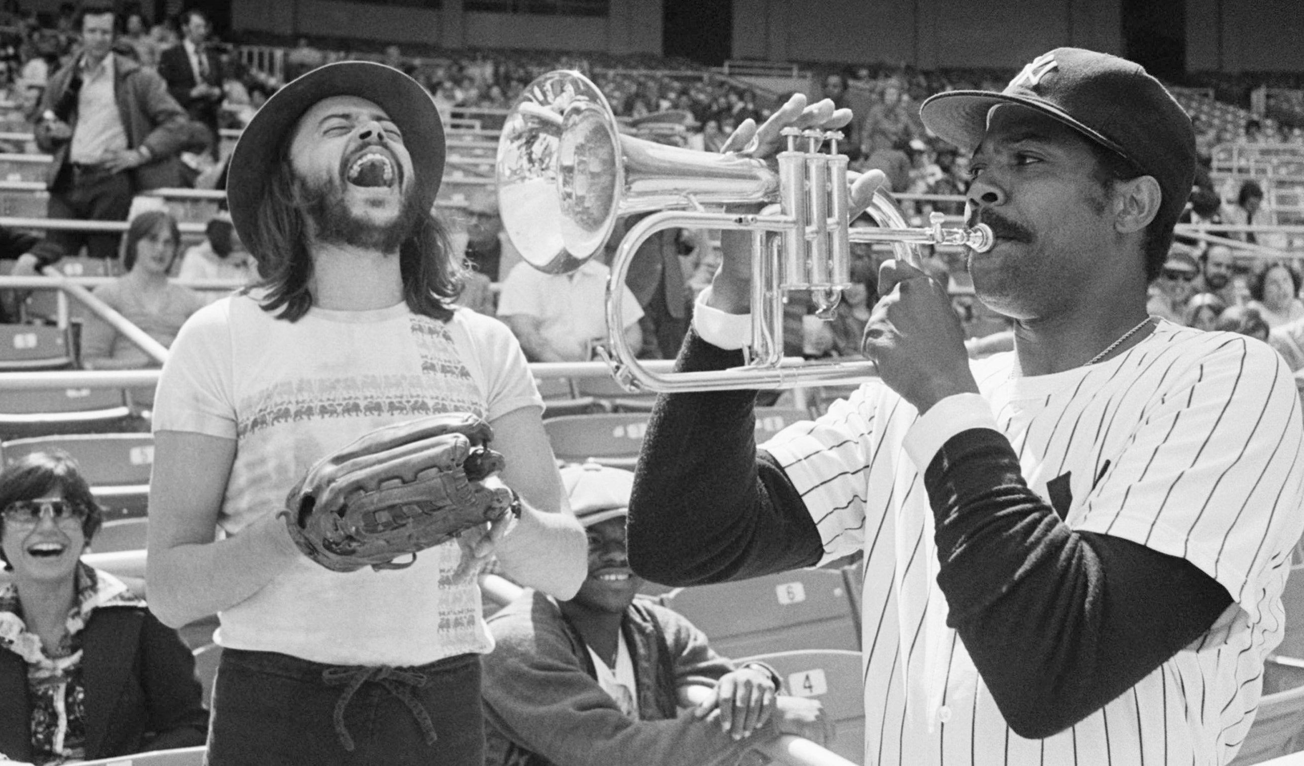 New York Yankees Pitcher Dock Ellis, right, has a little fun with a Chuck Mangione's horn before a game with the Toronto Blue Jays at Yankee Stadium on April 19, 1977, in New York.