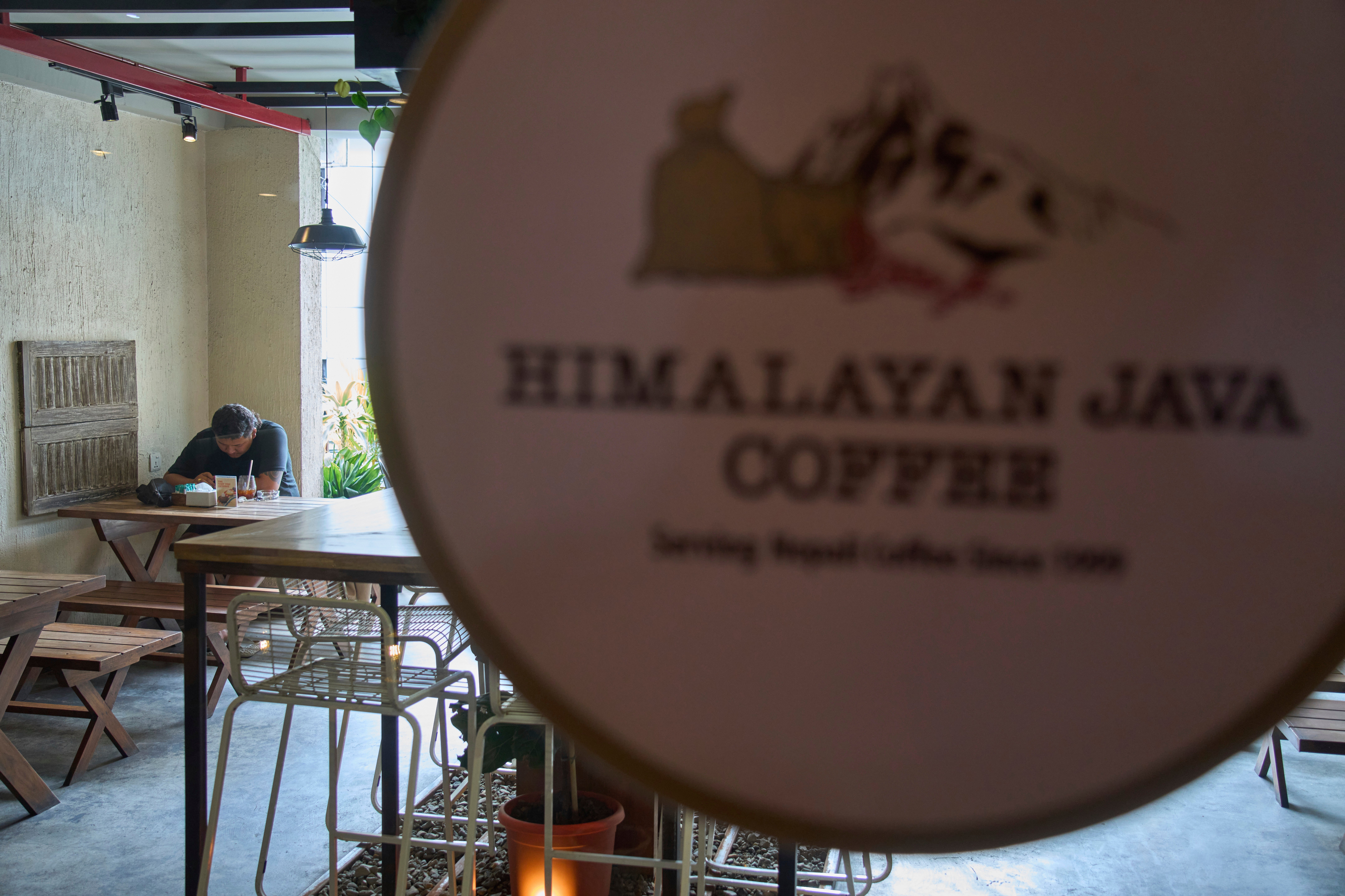 A person checks his mobile phone while drinking coffee at a cafe in Kathmandu, Nepal, Tuesday, June 10, 2025. (AP Photo/Niranjan Shrestha)