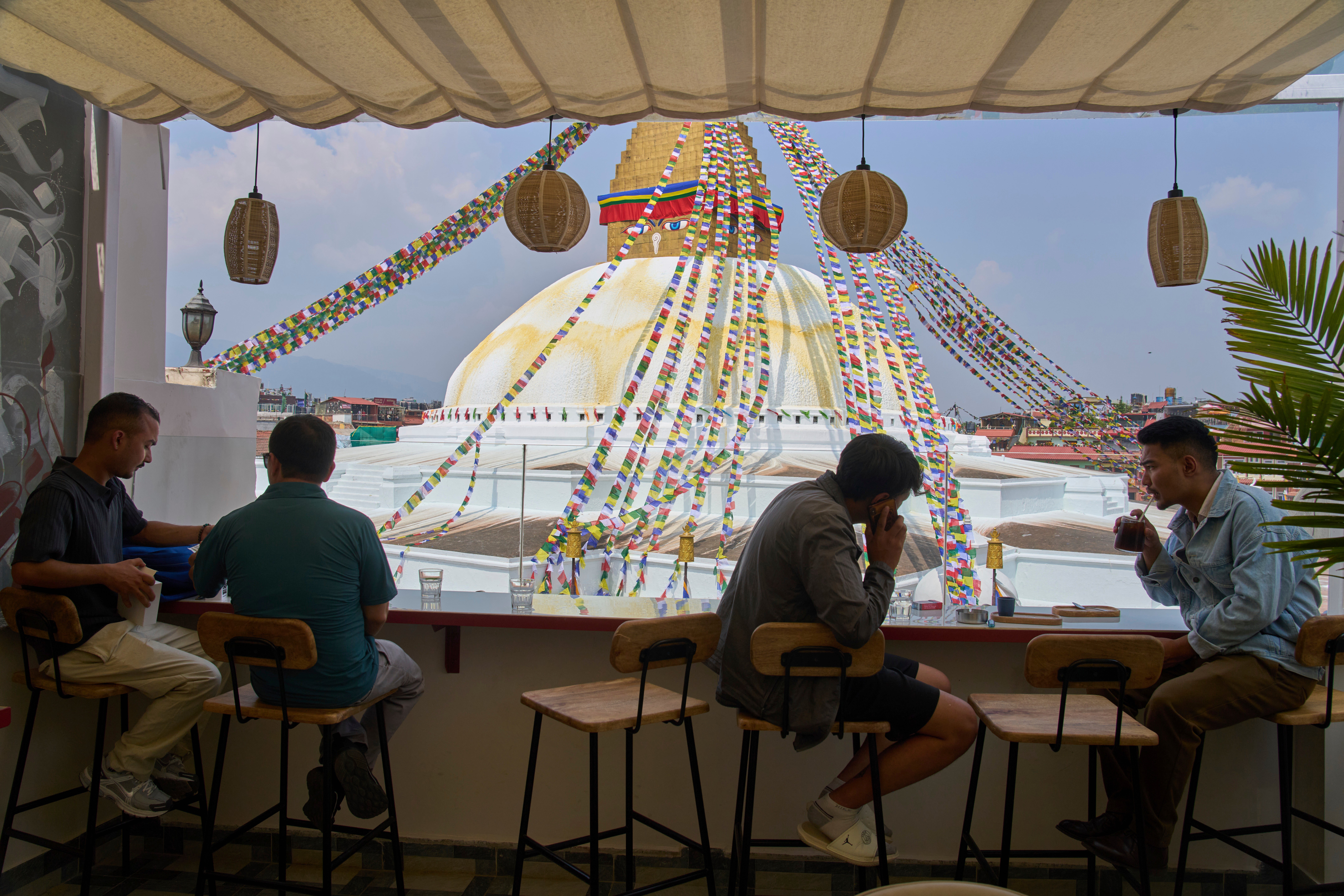 People drink coffee overlooking Boudhanath Stupa at Himalayan Java cafe in Kathmandu, Nepal, Tuesday, June 10, 2025. (AP Photo/Niranjan Shrestha)