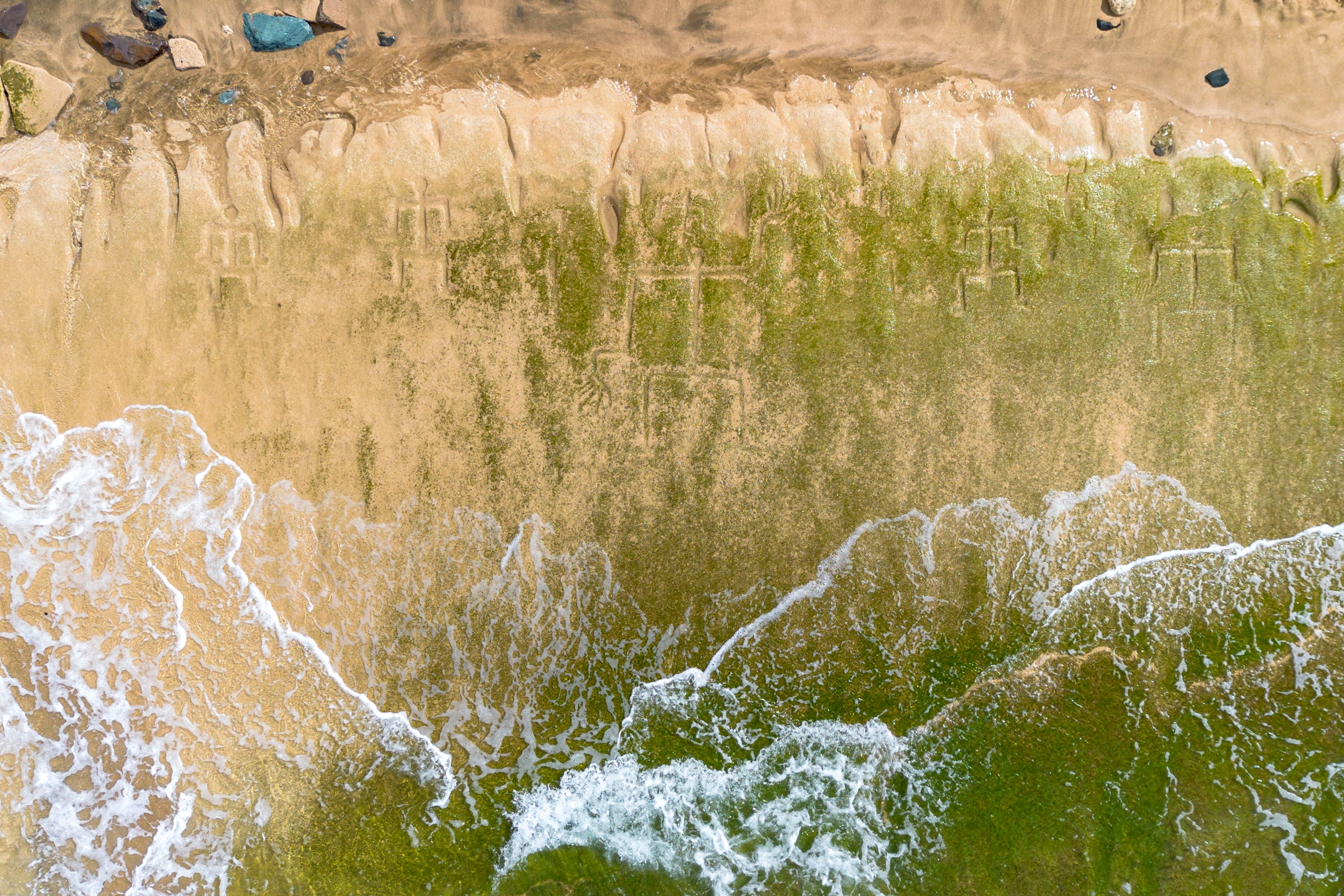 A drone view shows petroglyphs carved into the rock surface at Pokai Bay, July 22, 2025, in Waianae, Hawaii. (AP Photo/Mengshin Lin)