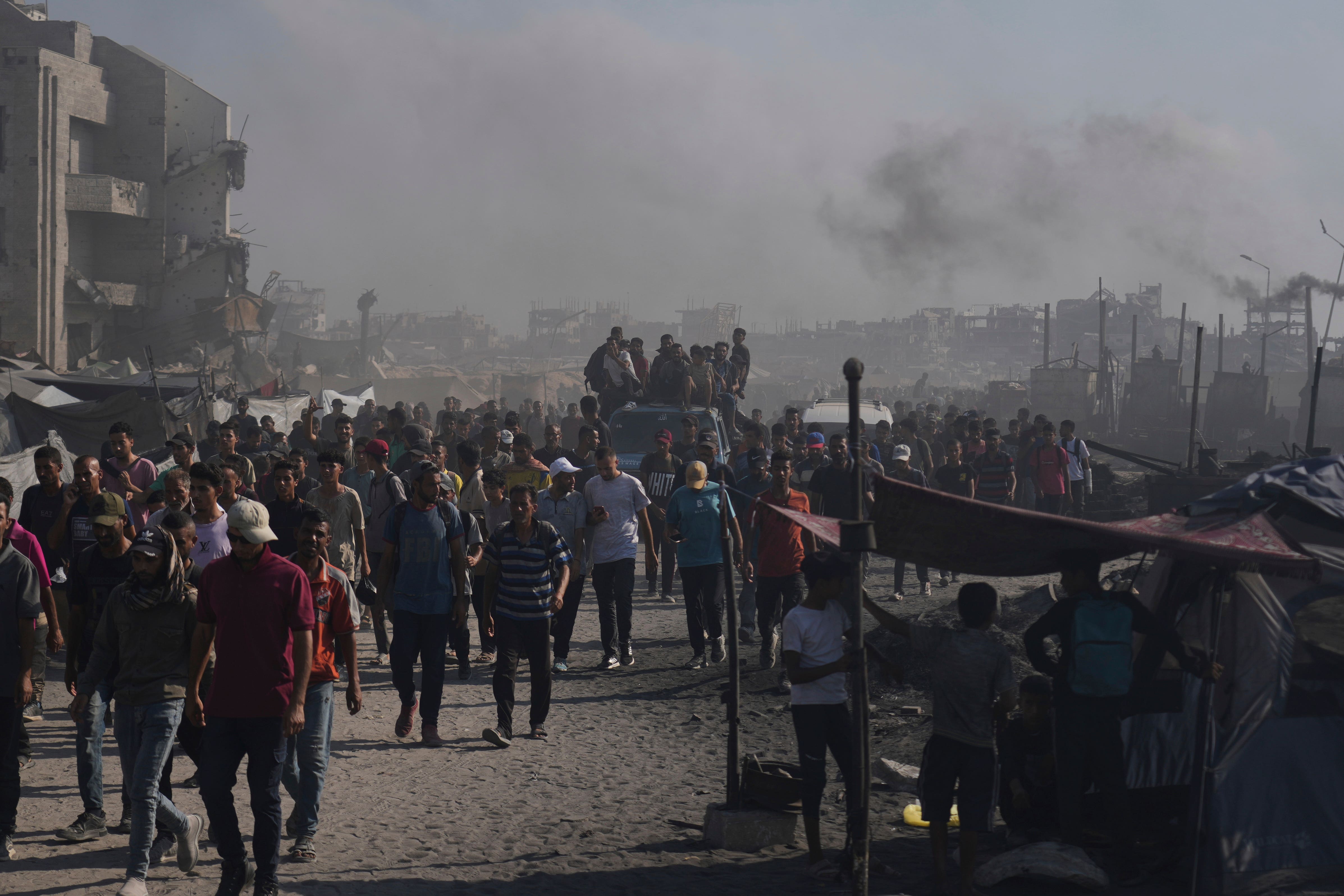 Palestinians walk along a road towards an area in the northern Gaza Strip where trucks are entering with humanitarian aid in Gaza City (Abdel Kareem Hana/AP)