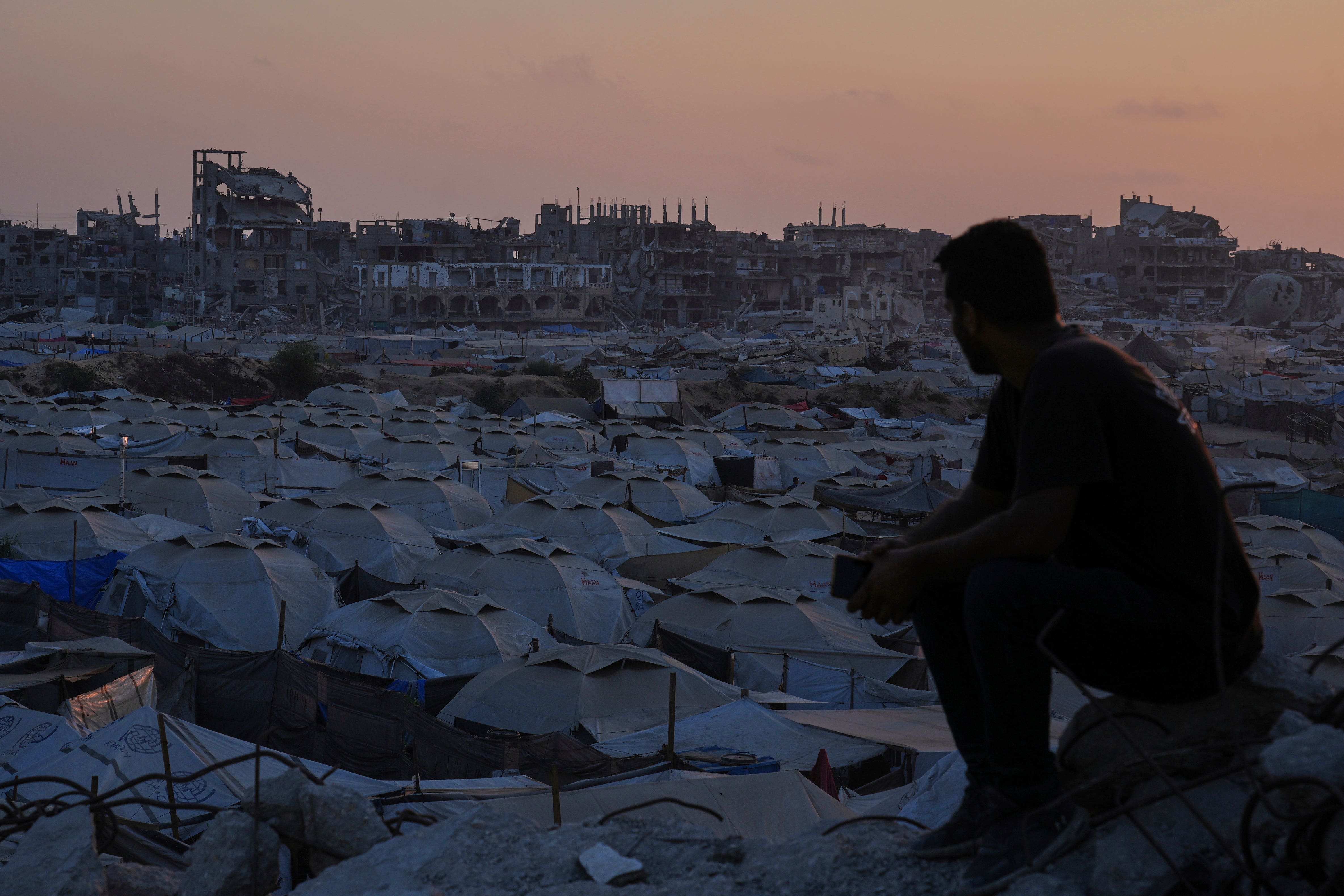 A Palestinian looks at a makeshift tent camp for people who were displaced by the Israeli air and ground operations in the Gaza Strip (Abdel Kareem Hana/AP)