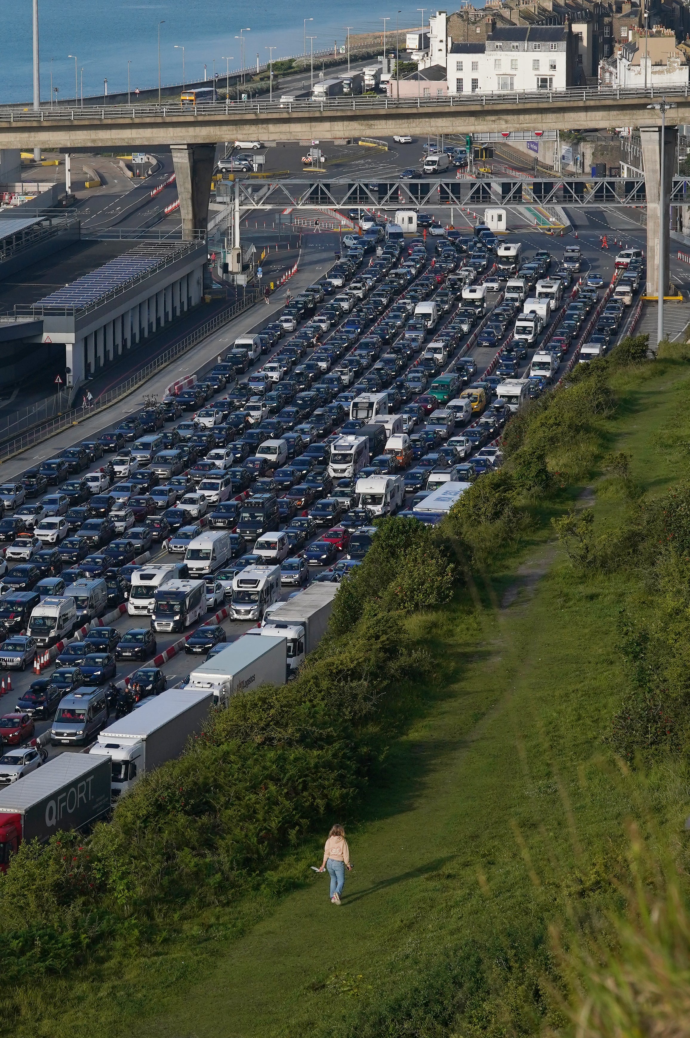 A woman walks across the cliffs while holiday and freight traffic queue to use the Port of Dover (Gareth Fuller/PA)