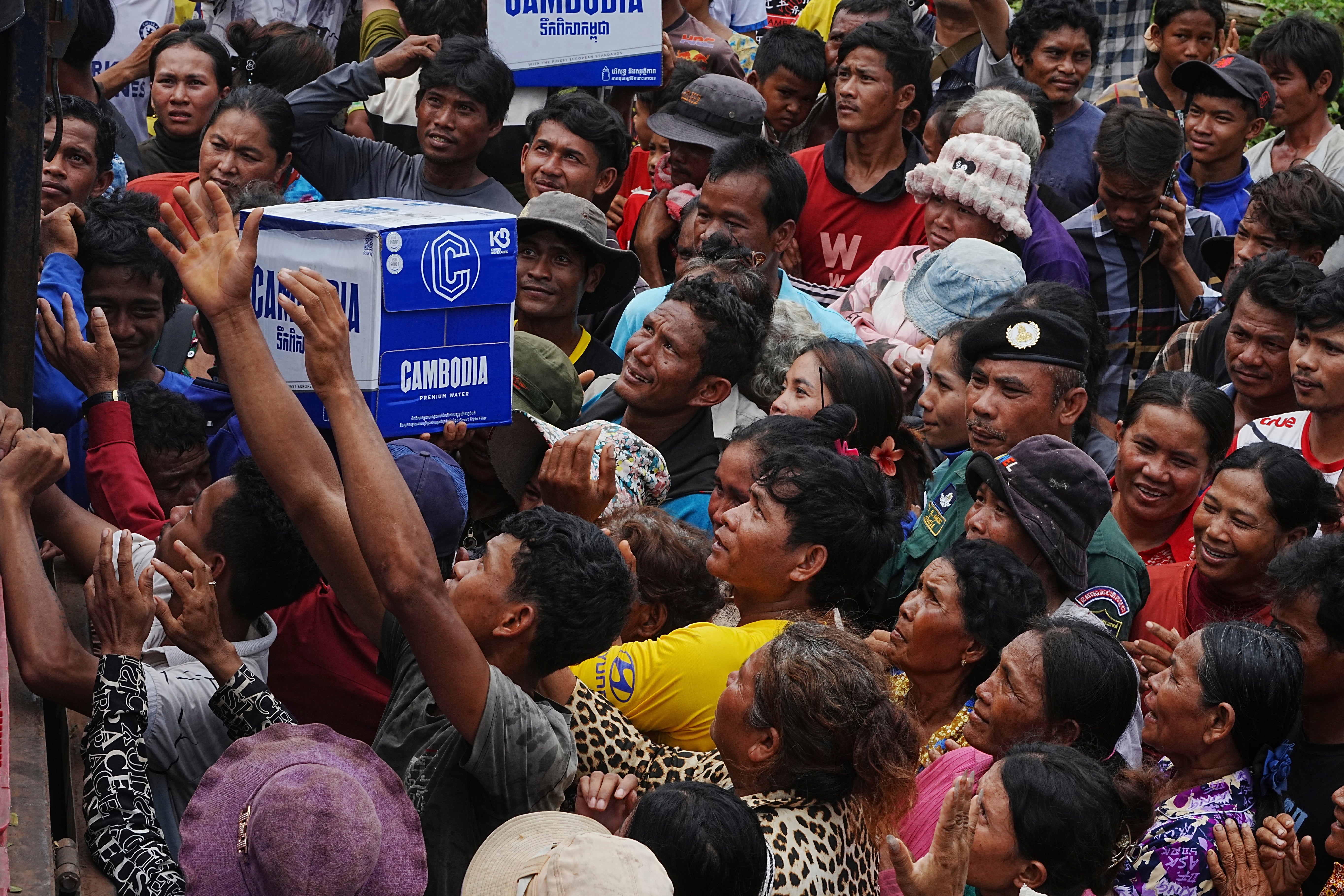 Cambodians displaced by the fighting crowd to receive drinking water donated by a local company as they take refuge in a primary school in Oddar Meanchey province
