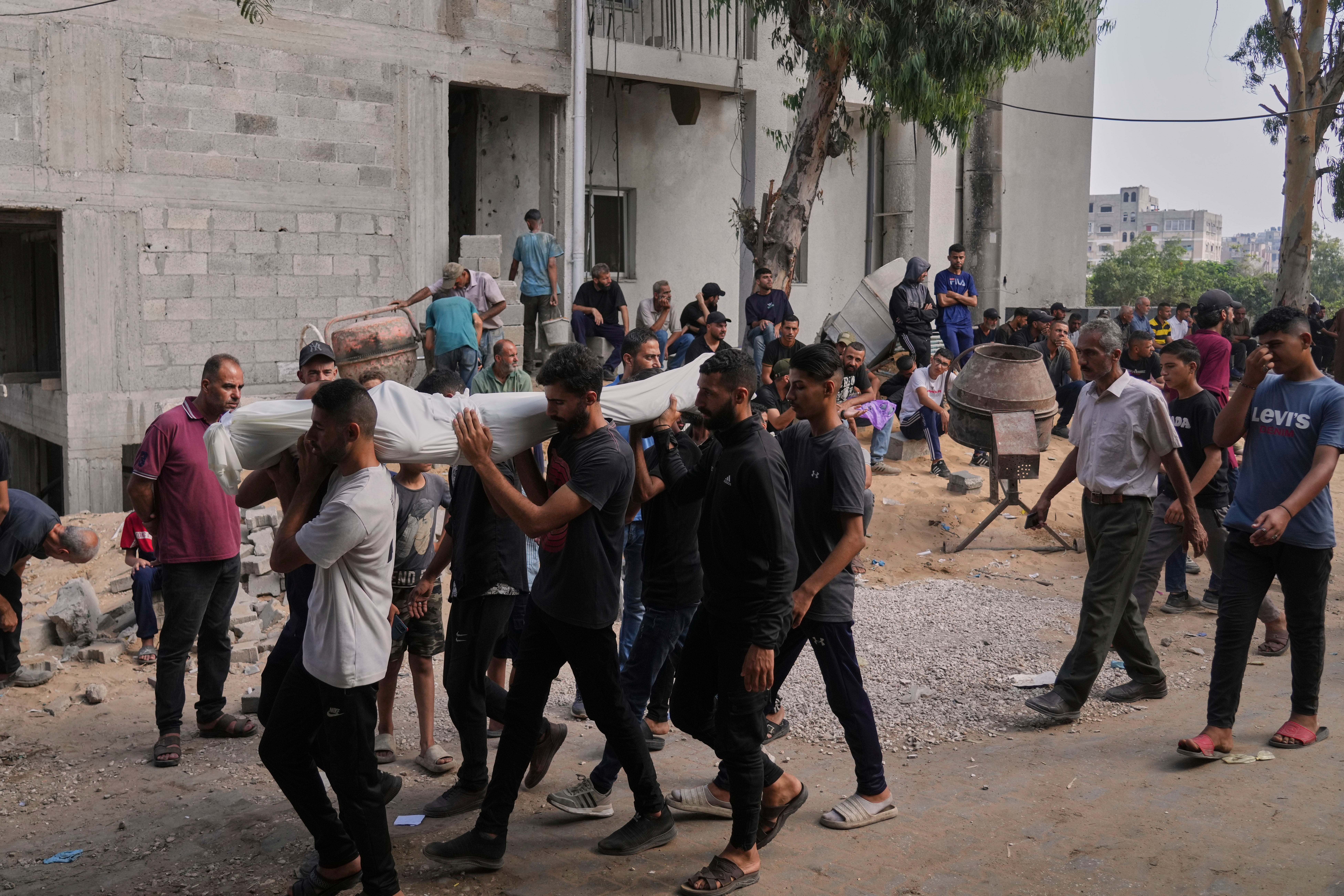Palestinians carry the body of a person who was killed while trying to reach aid trucks