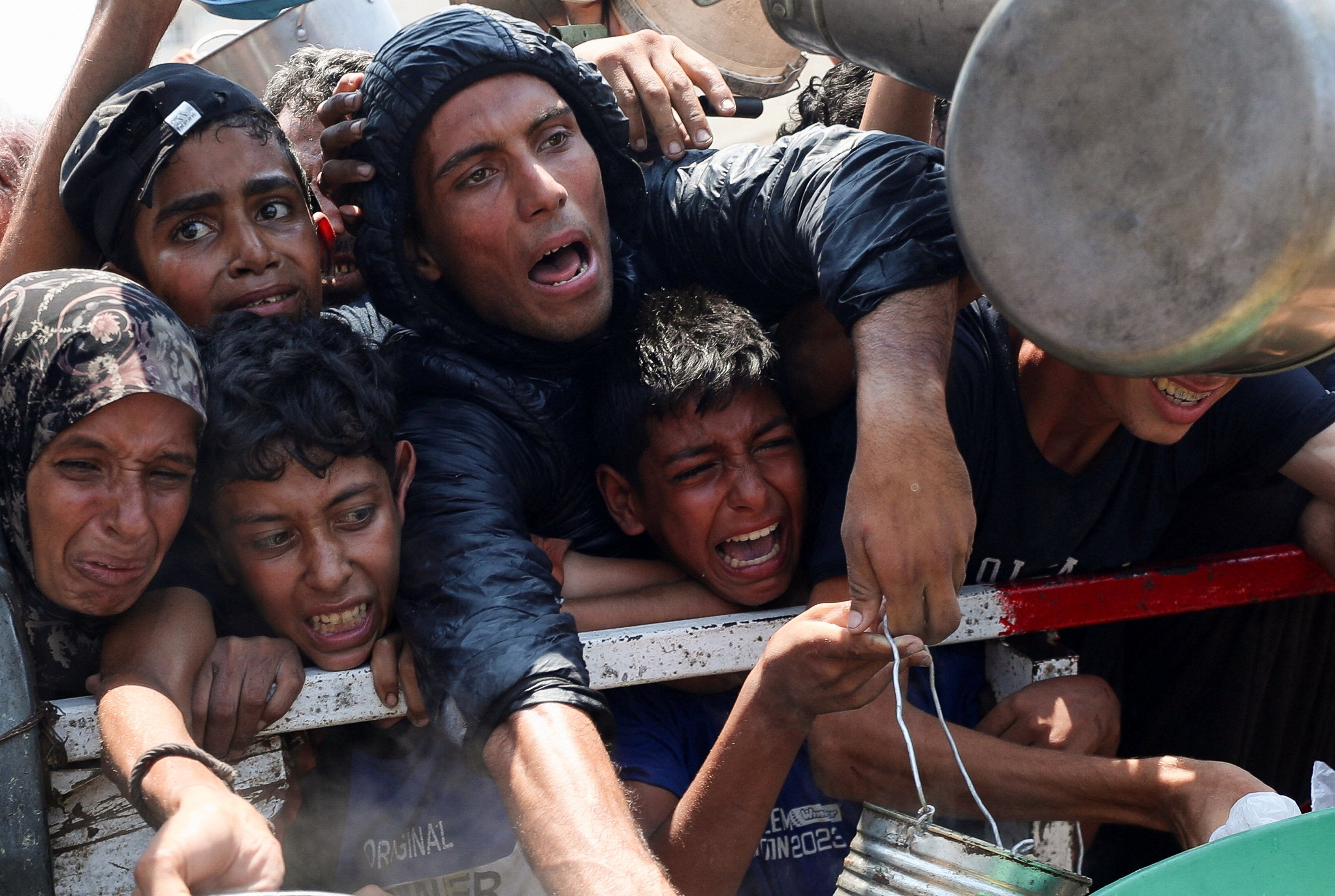 Starving Palestinians desperately seek food at an aid kitchen in Gaza City on Saturday