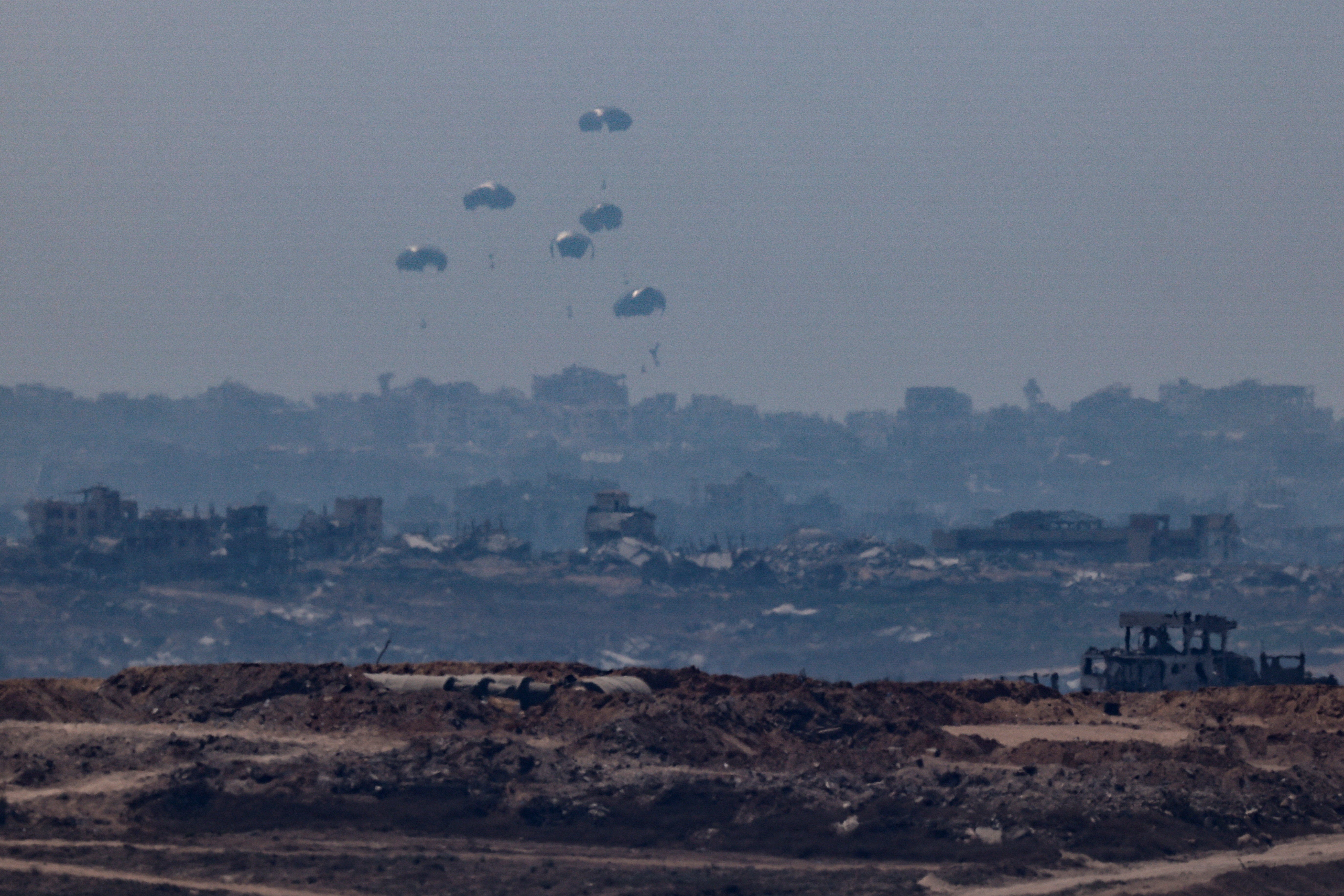 An aircraft drops humanitarian aid packages over the Gaza Strip, as seen from Israel