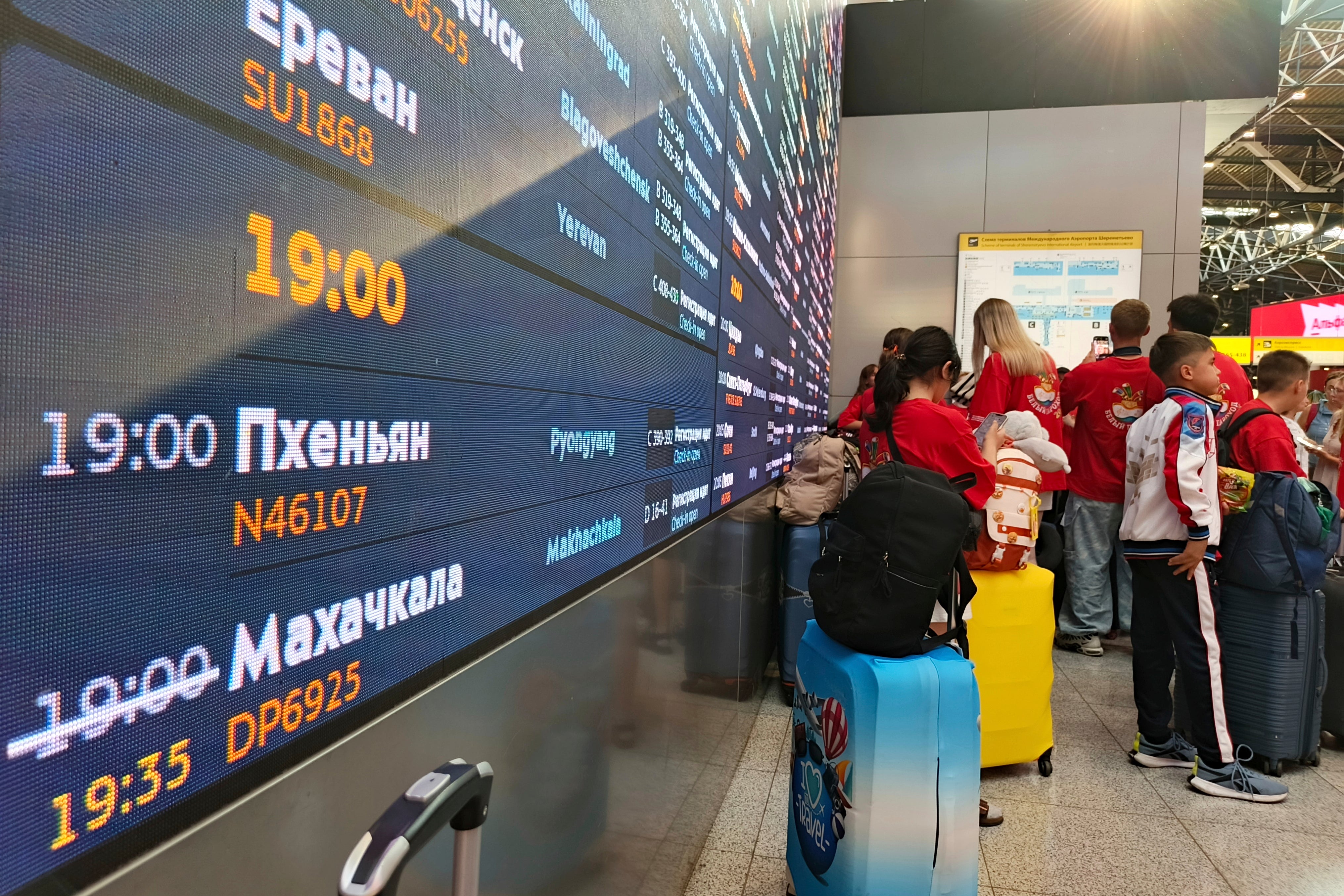 Passengers lineup to check-in for the first flight connecting Moscow and Pyongyang with a flight information board showing take-off time, at Moscow's Sheremetyevo International airport