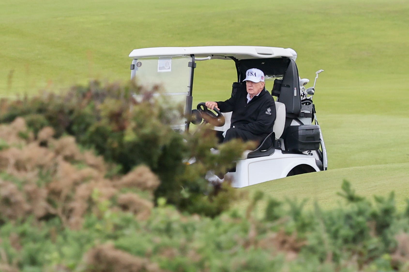 US President Donald Trump steers a golf cart at his Trump Turnberry resort (Robert Perry/PA)