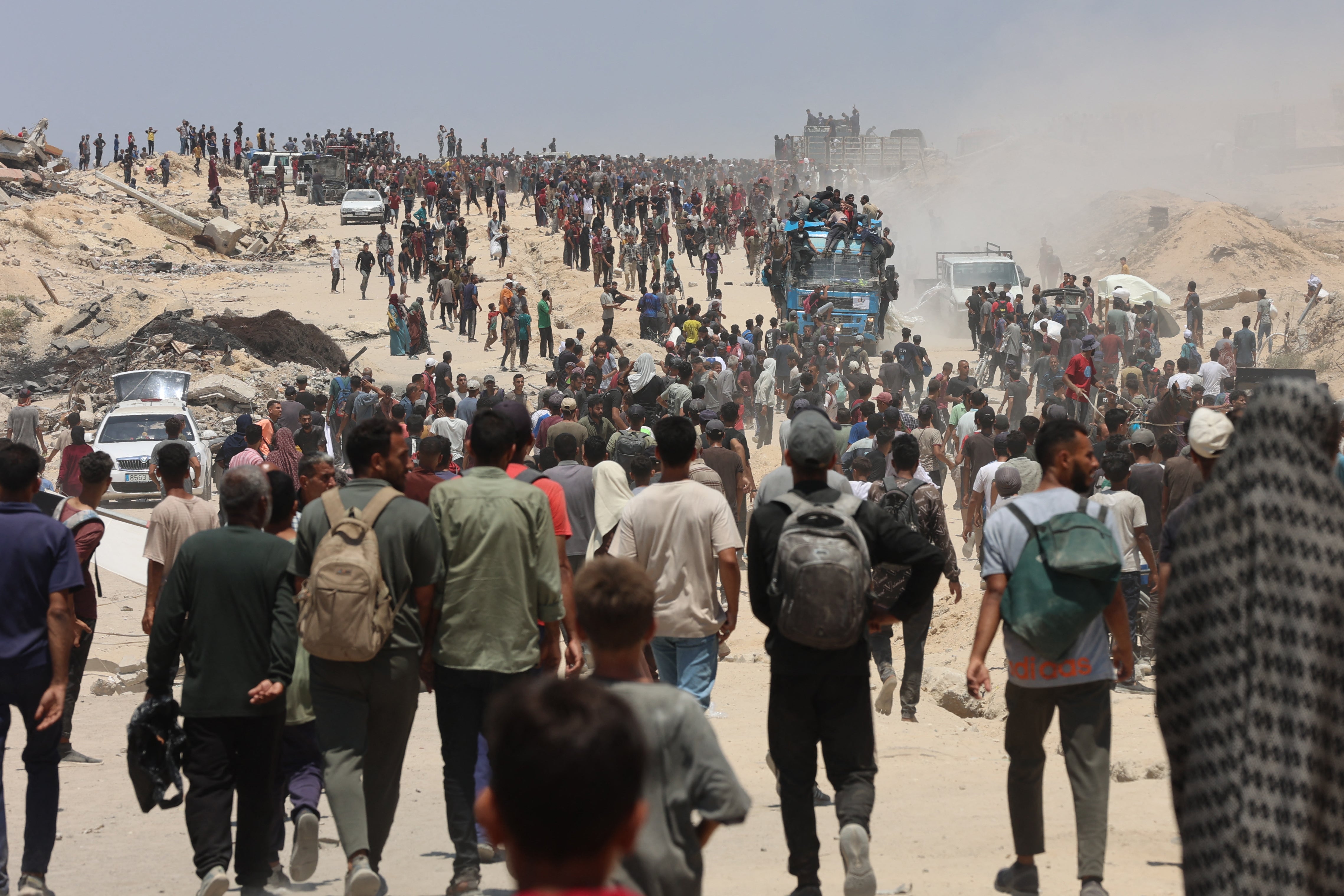 People make their way towards trucks carrying humanitarian aid in western Jabalia