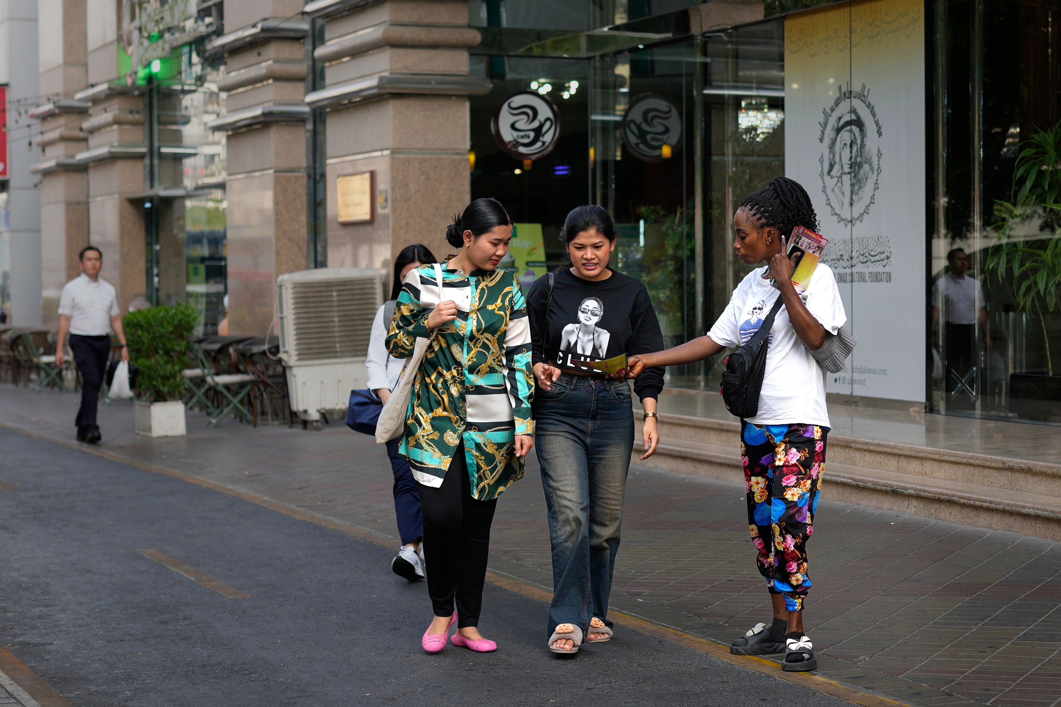 A migrant worker hands out beauty salon pamphlets to passersby at a marketplace in Dubai, United Arab Emirates, Friday, July 4, 2025. (AP Photo/Altaf Qadri)