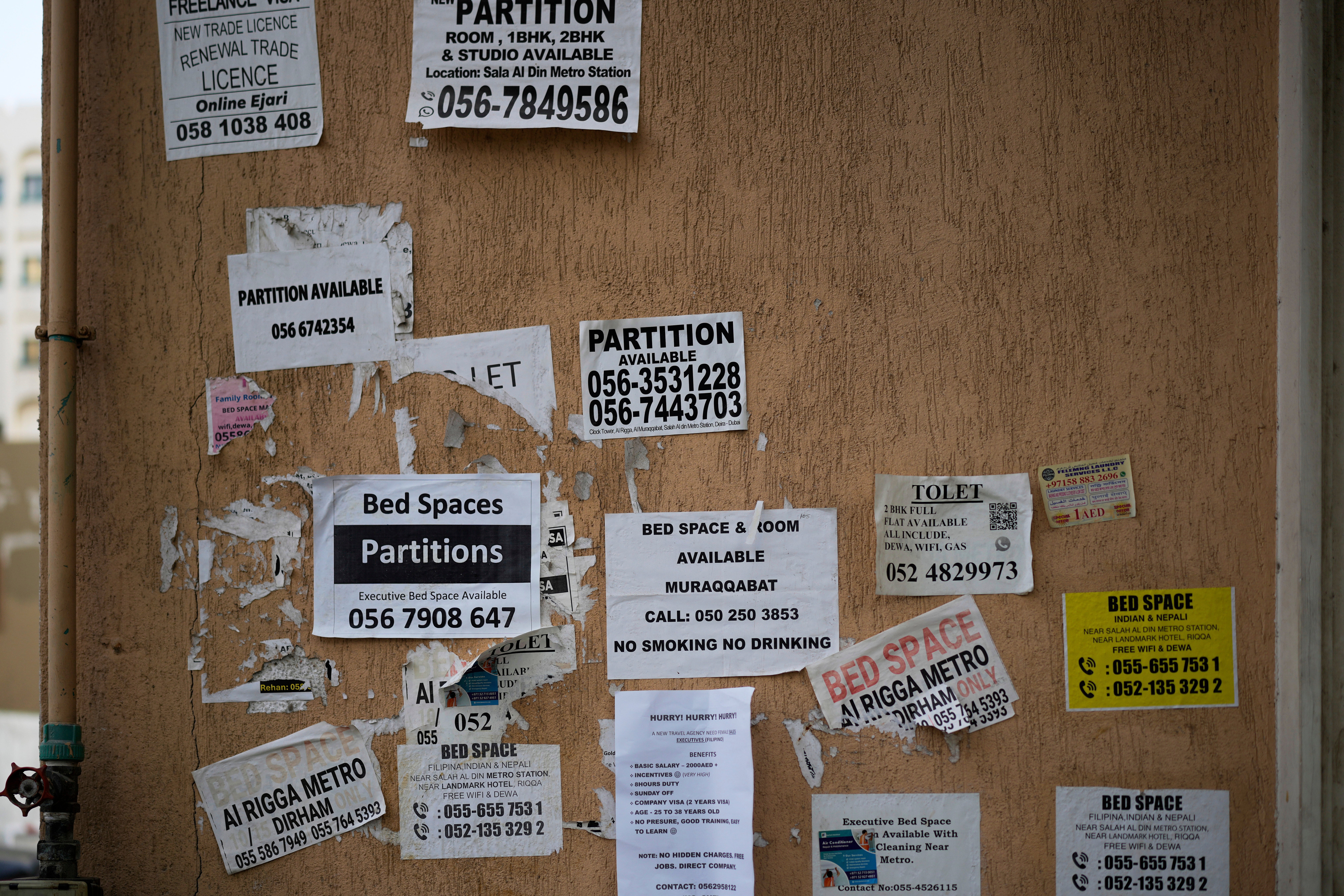 The wall of a building is plastered with advertisements for inexpensive, partitioned housing in Dubai, United Arab Emirates, Friday, July 4, 2025. (AP Photo/Altaf Qadri)