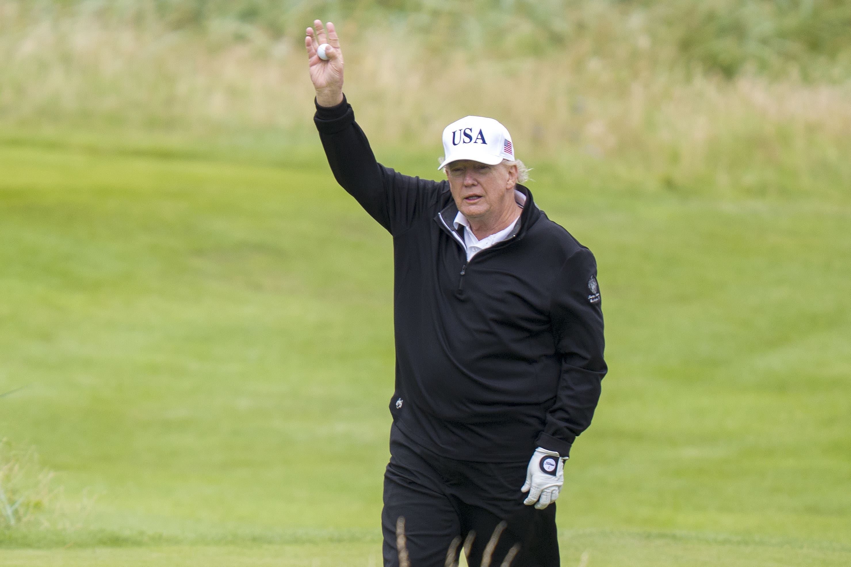 Donald Trump waves as he plays golf (Jane Barlow/PA)