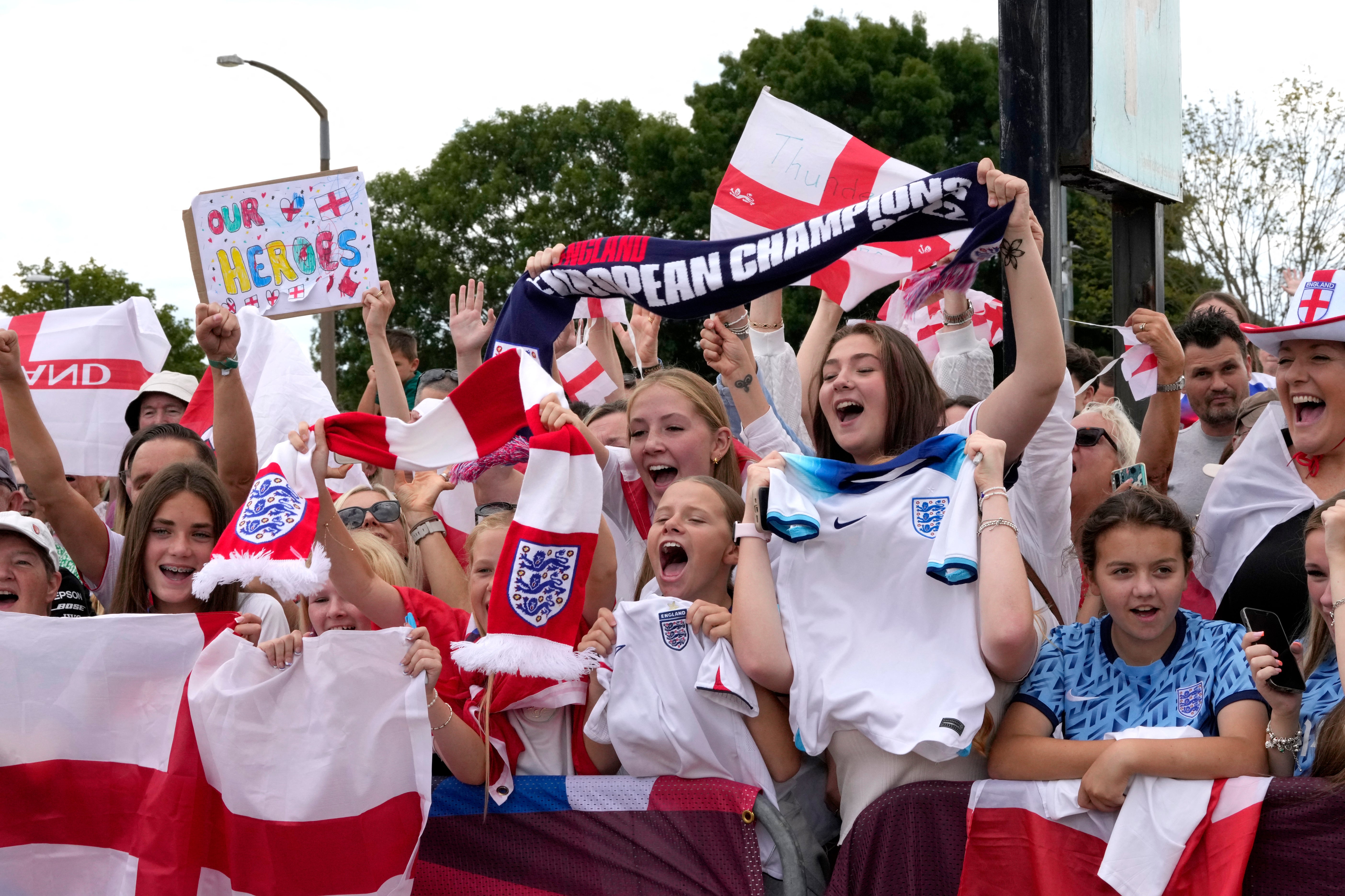 Fanoušci čekají s bannery a vlajkami, aby přivítali anglický ženský národní fotbalový tým na letišti Southend