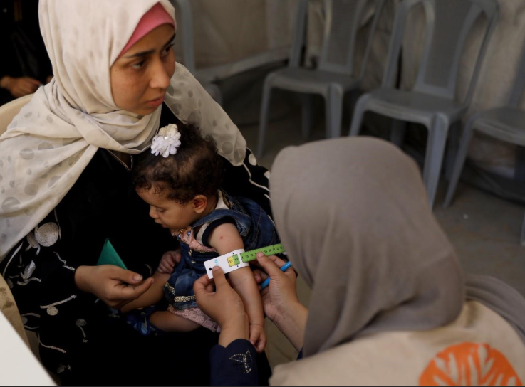A mother and her child being screened for malnutrition at a clinic in Gaza