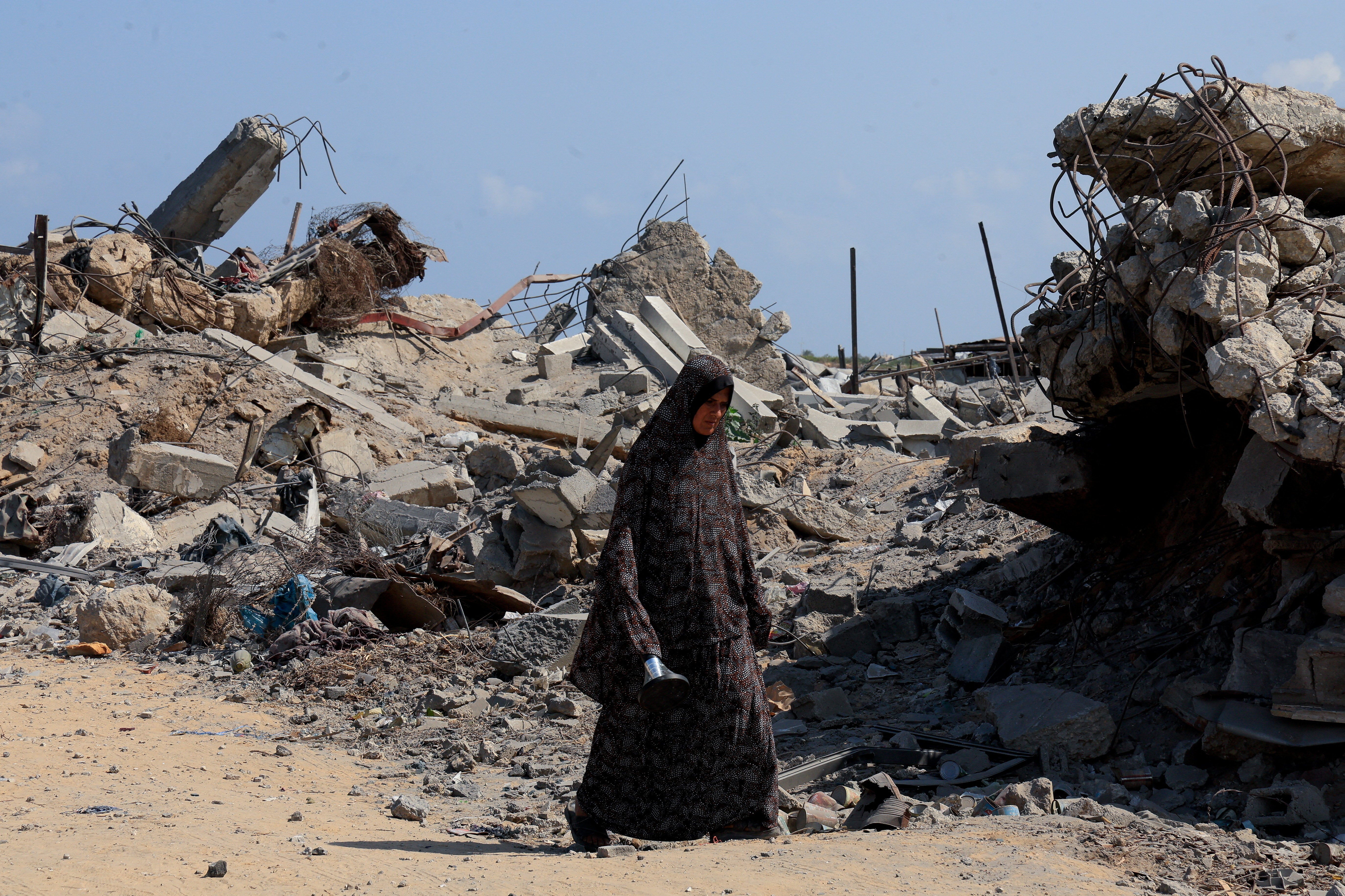A Palestinian woman walks at the site of houses destroyed during an Israeli raid in the western part of Nuseirat, central Gaza Strip