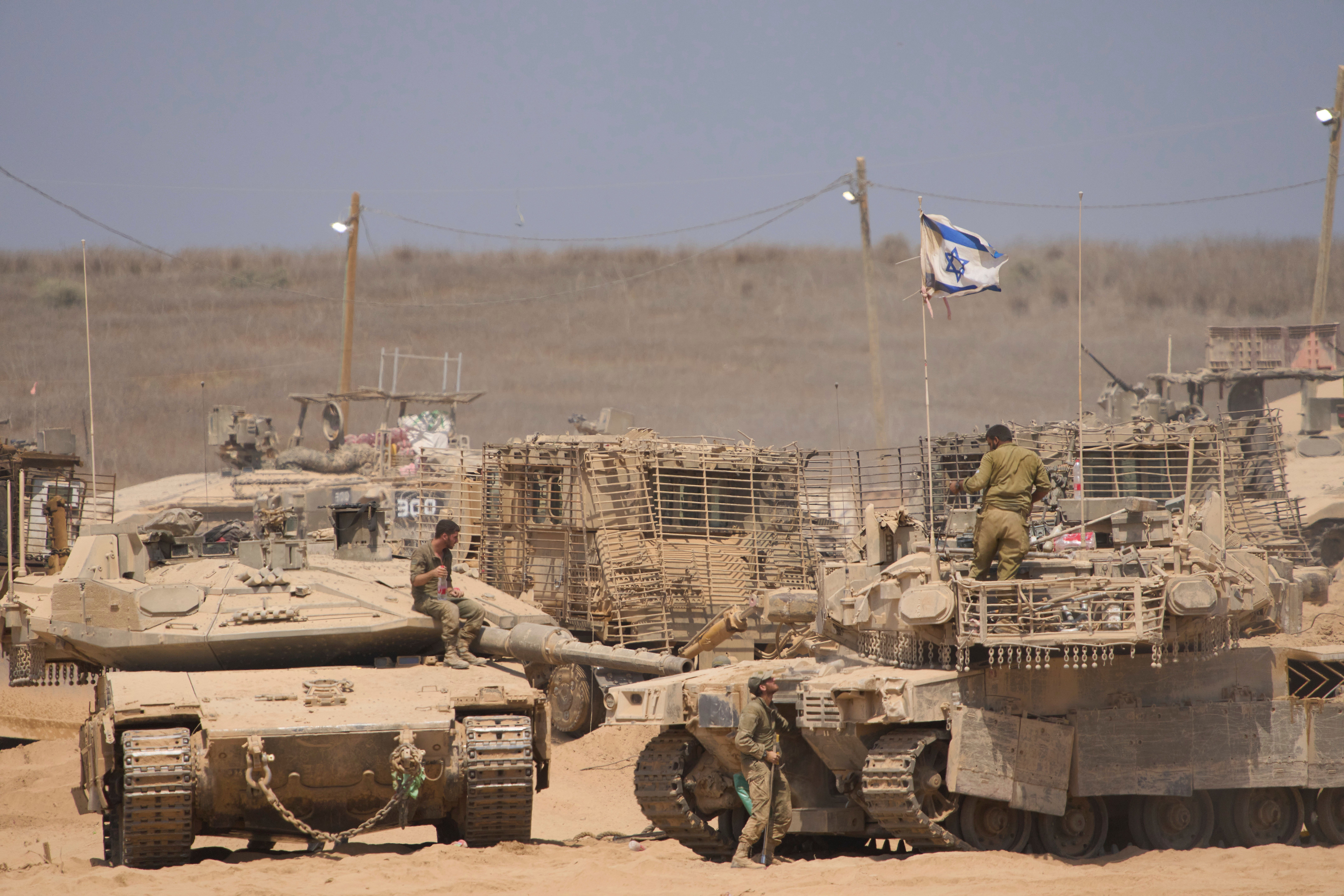 Israeli soldiers work on their tanks in a staging area on the border with the Gaza Strip, in southern Israel, on 29 July