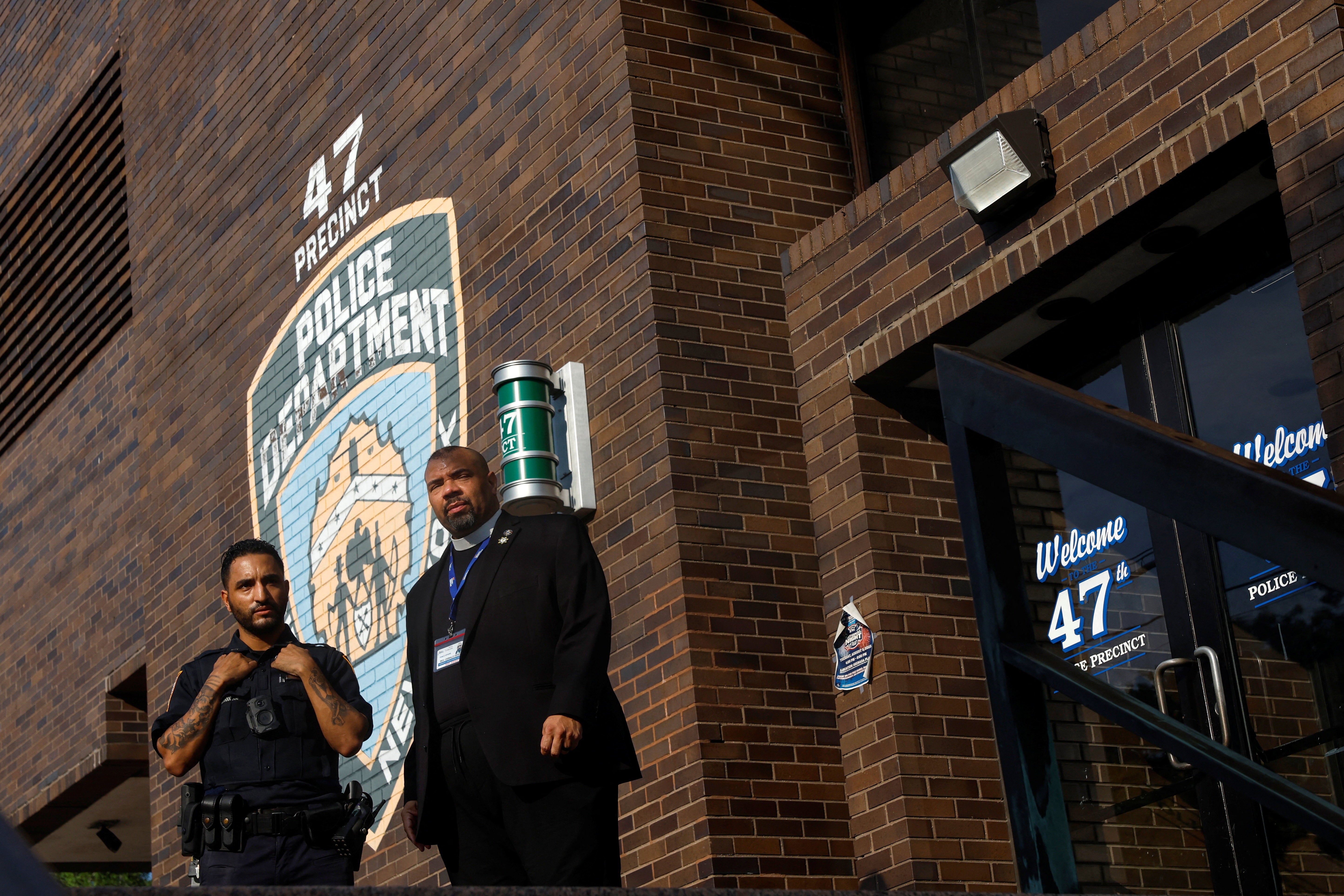 Rev. Oswald Denis speaks with a New York Police Department officer outside the 47th precinct, which was the police station for the New York Police Department's Didarul Islam who was killed in the deadly mass shooting