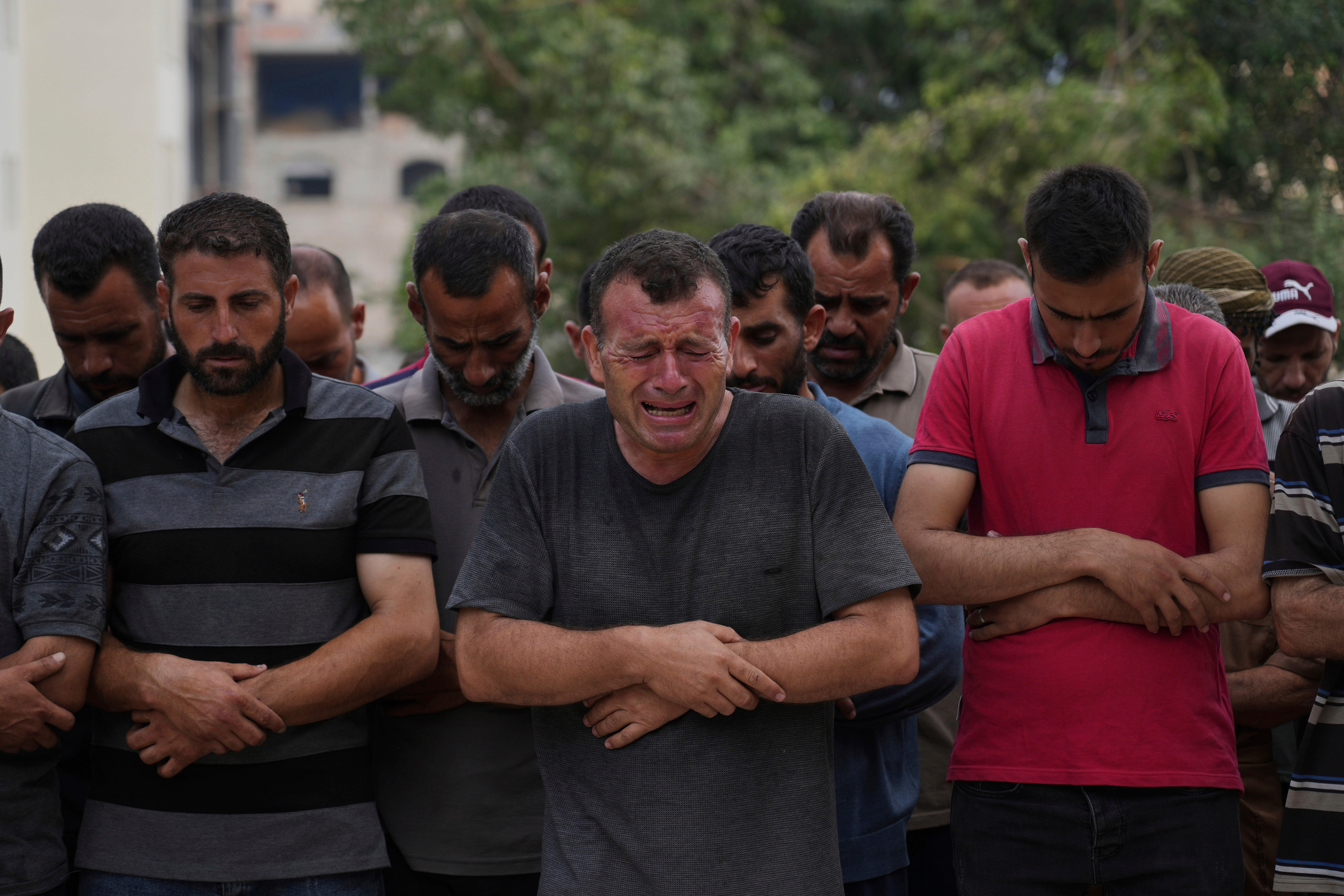 A group of Palestinians pray next to the body of a person killed while trying to reach aid trucks entering northern Gaza through the Zikim crossing with Israel