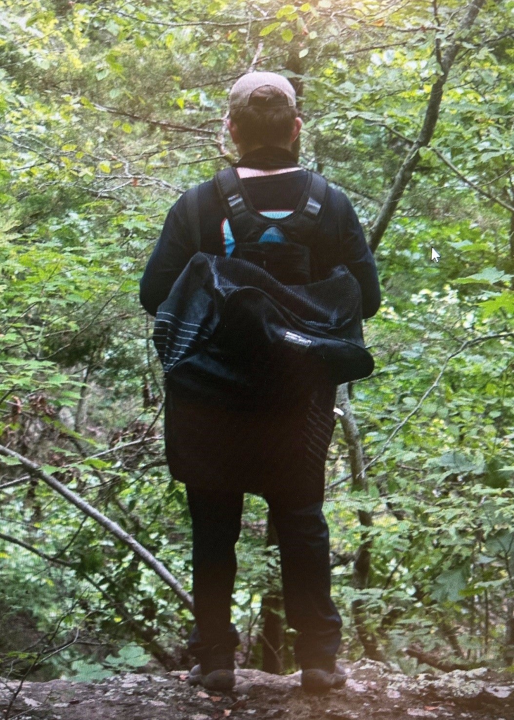 Police released a photo of the person of interest from behind, showing him in dark clothes with a dark backpack