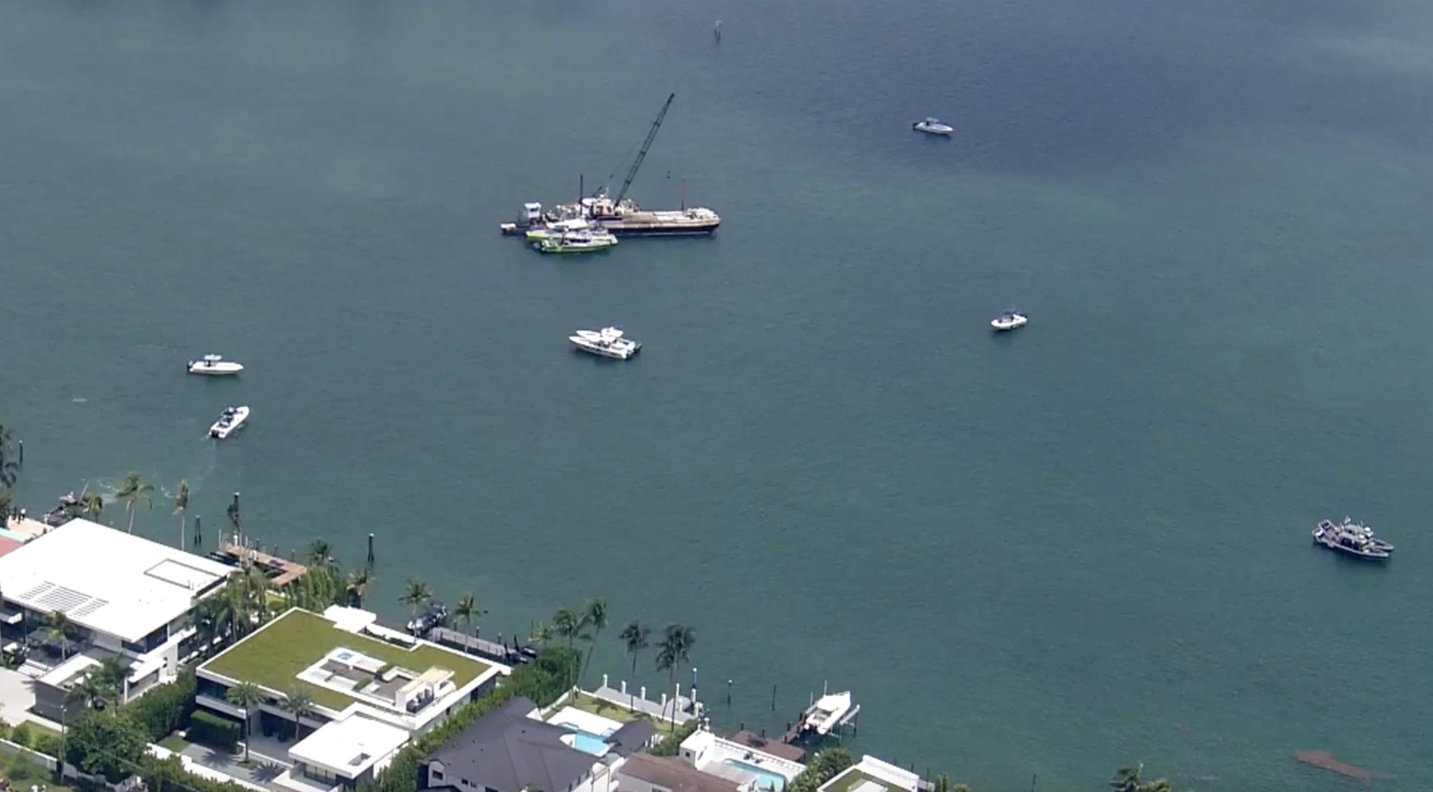 Miami-Dade Fire Rescue and others in boats around what appears to be a barge involved in an accident with a group of kids and an adult on a sailing boat during a sailing camp