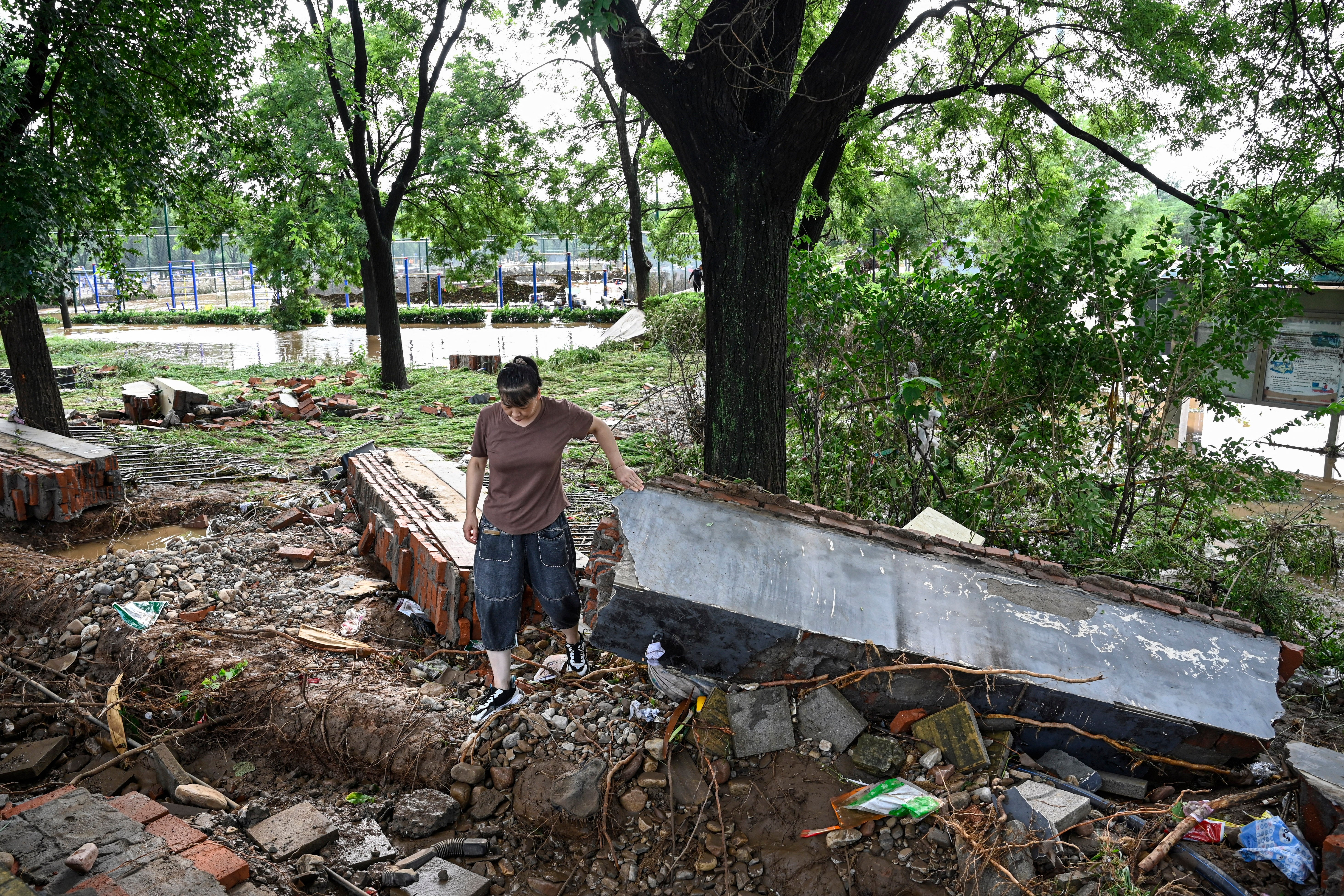 A resident walks on the debris in the aftermath of flooding from heavy rains at Taishitun village in Miyun district
