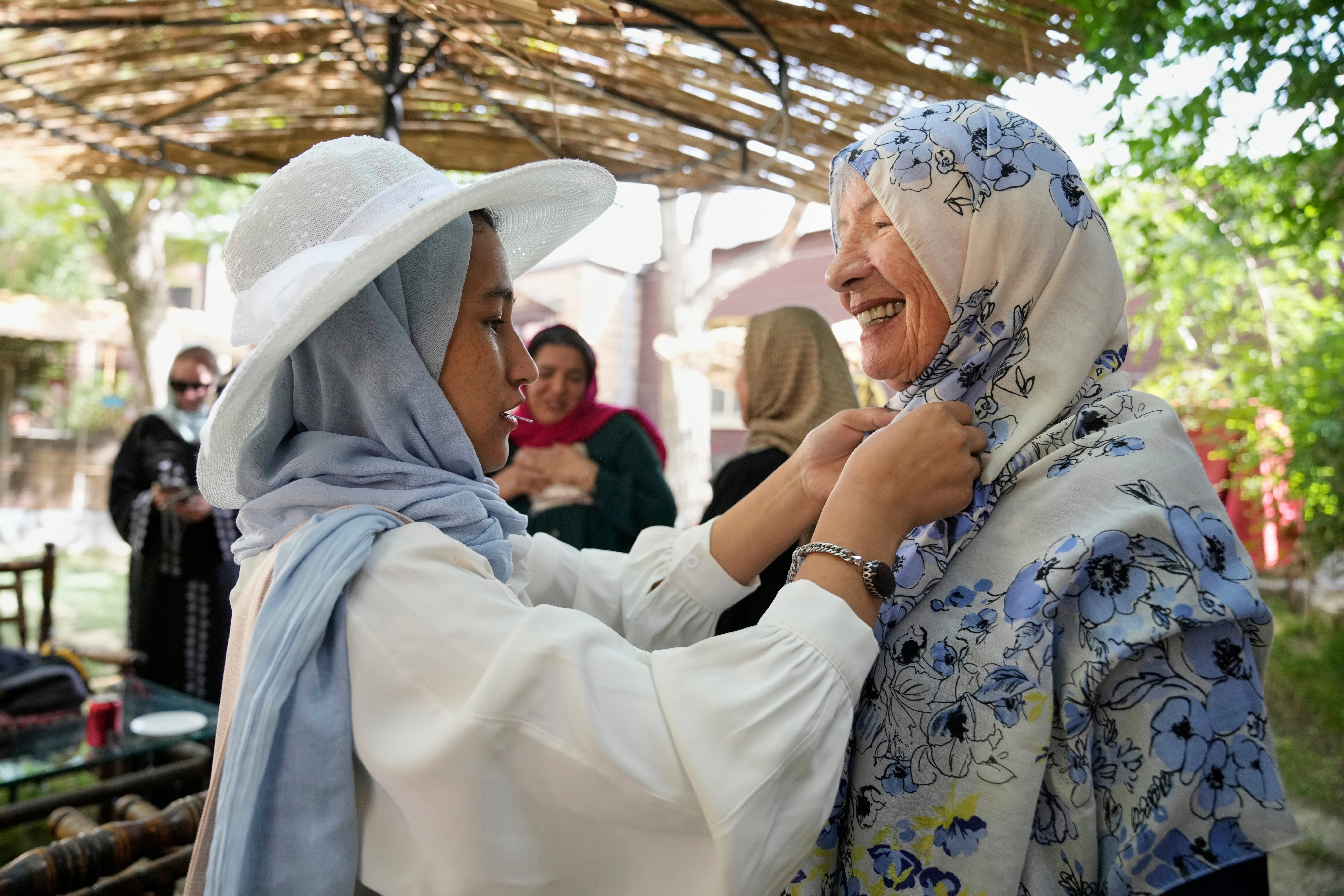 Maryam, a young Afghan on her first day of training to become a tour guide, helps 82-year-old Australian tourist Suzanne Sandral adjust her hijab in Kabul, Afghanistan, Wednesday, May 28, 2025. (AP Photo/Ebrahim Noroozi)
