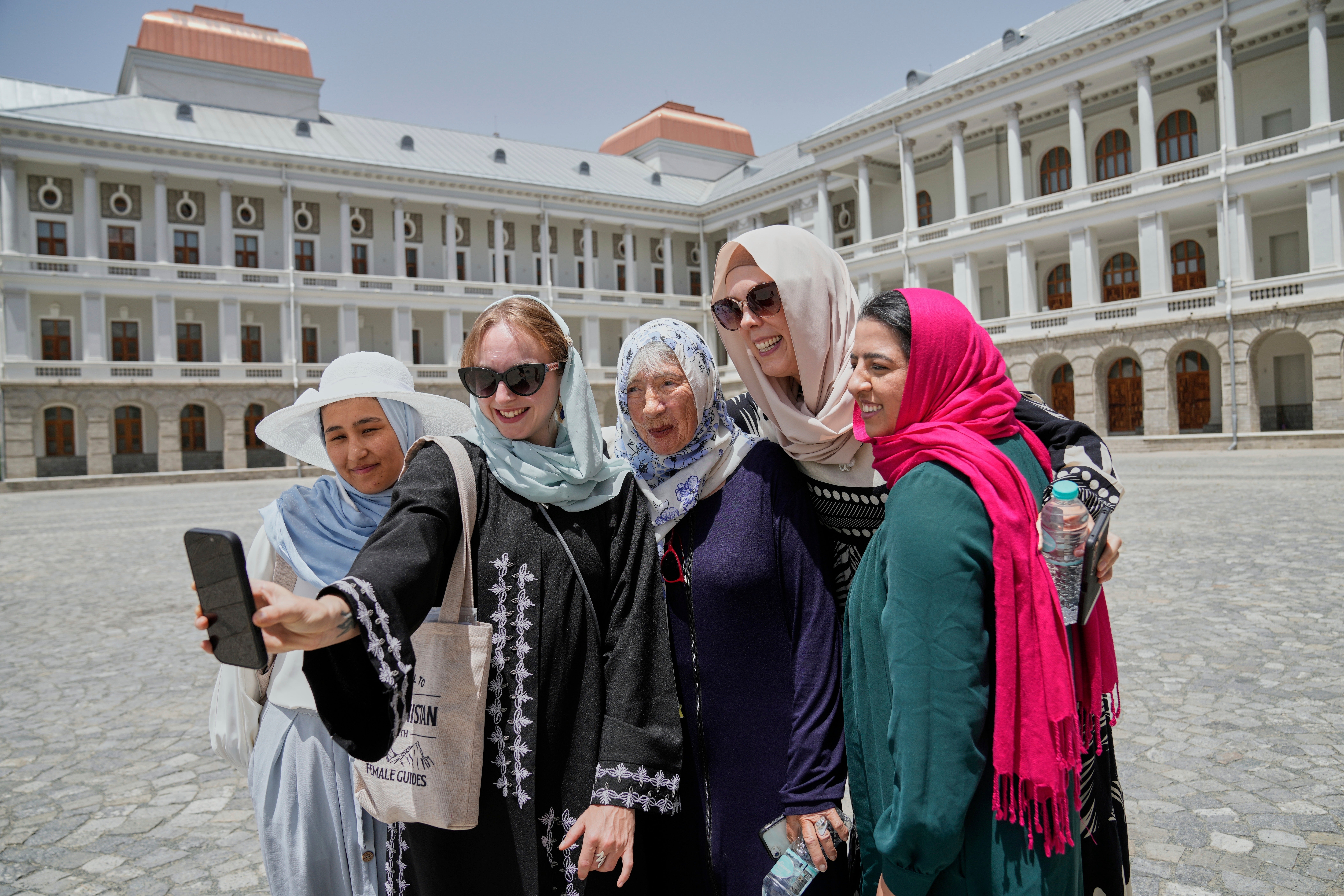 Zoe Stephens, 31, from Britain, takes a selfie with other foreign, female tourists and Maryam, a local trainee tour guide, at left, at Darul Aman Palace in Kabul, Afghanistan, Wednesday, May 28, 2025. (AP Photo/Ebrahim Noroozi)