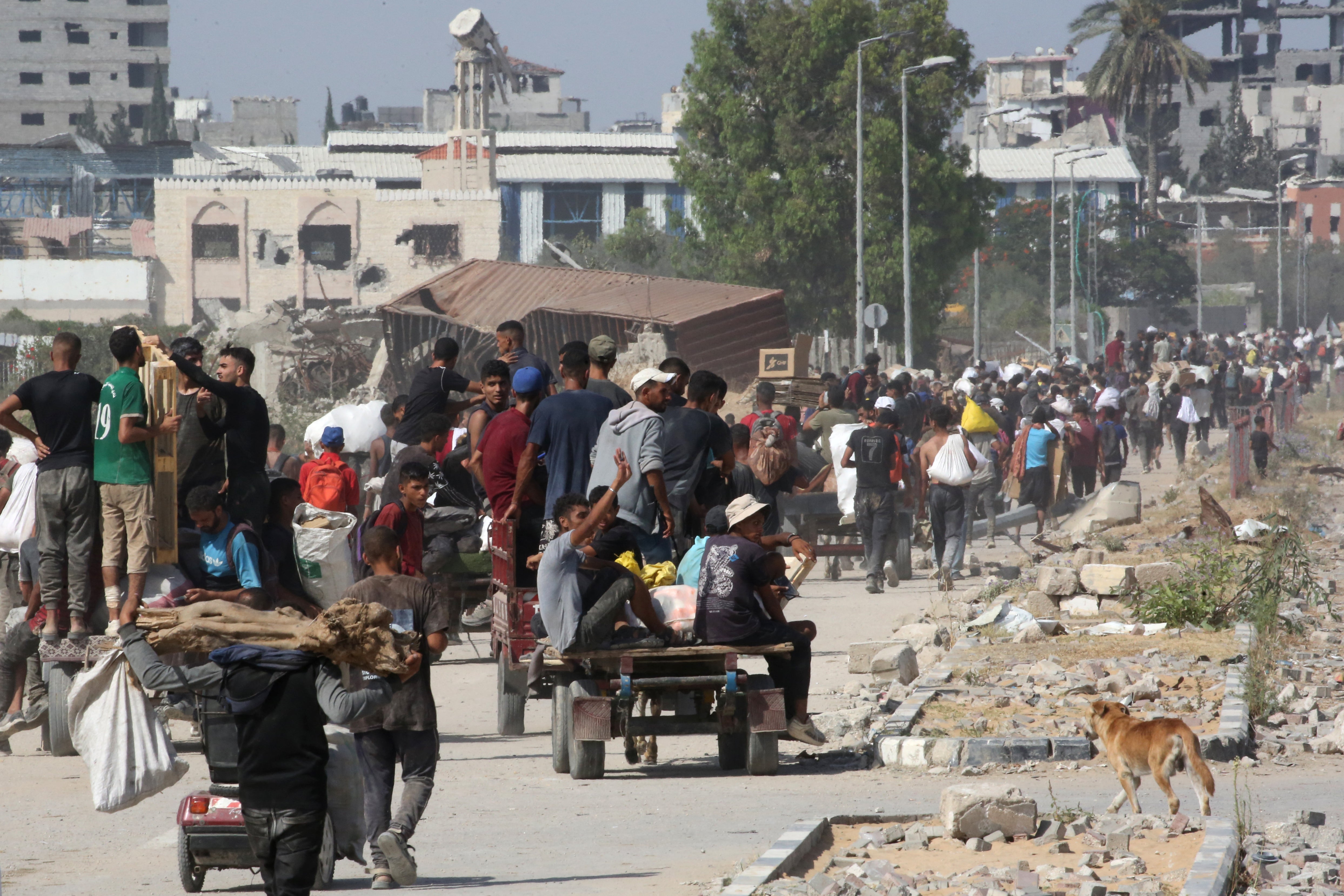Displaced Palestinians at the Nuseirat refugee camp haul food parcels and other items obtained from a GHF aid distribution point