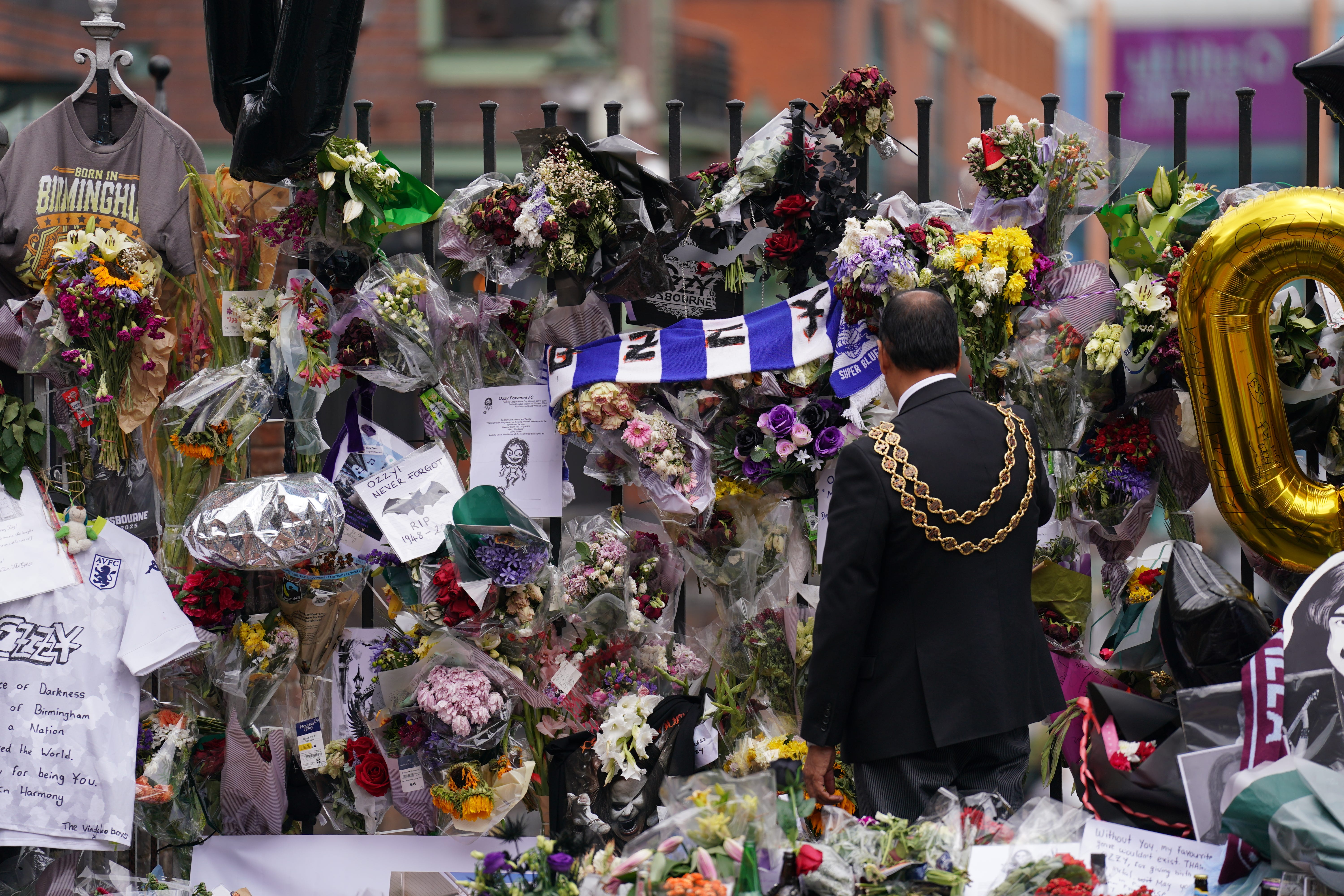 The lord mayor of Birmingham Zafar Iqbal views the messages and floral tributes left at the Black Sabbath Bridge bench on Broad Street in Birmingham in memory of Black Sabbath frontman Ozzy Osbourne (Joe Giddens/PA)