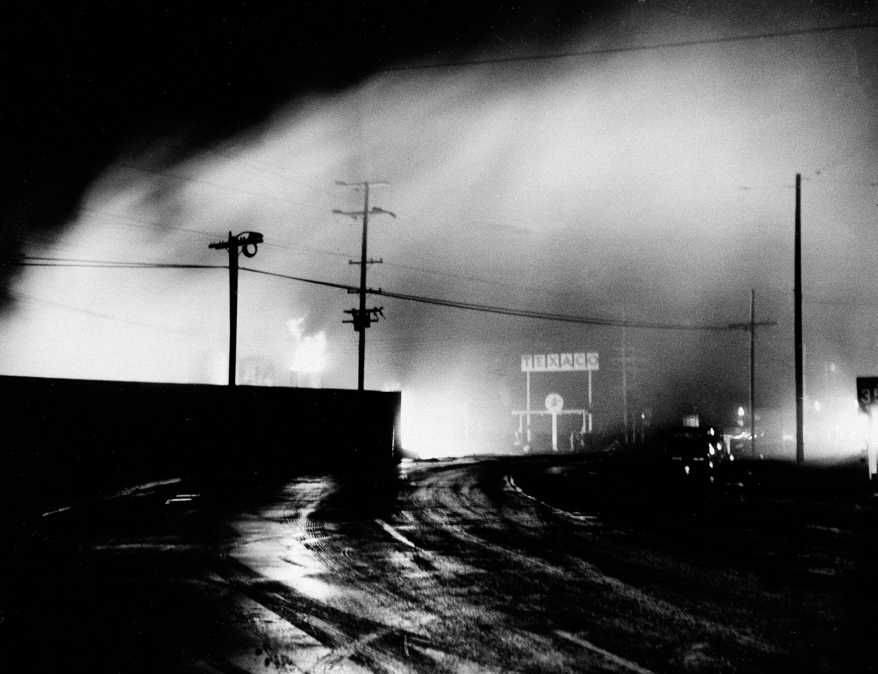 Gasoline storage tanks are shown burning in the early morning hours of March 28, 1964, on the outskirts of Crescent City, Calif., after being ignited by power lines broken by the tidal wave caused by an earthquake in Alaska. (AP Photo, File)