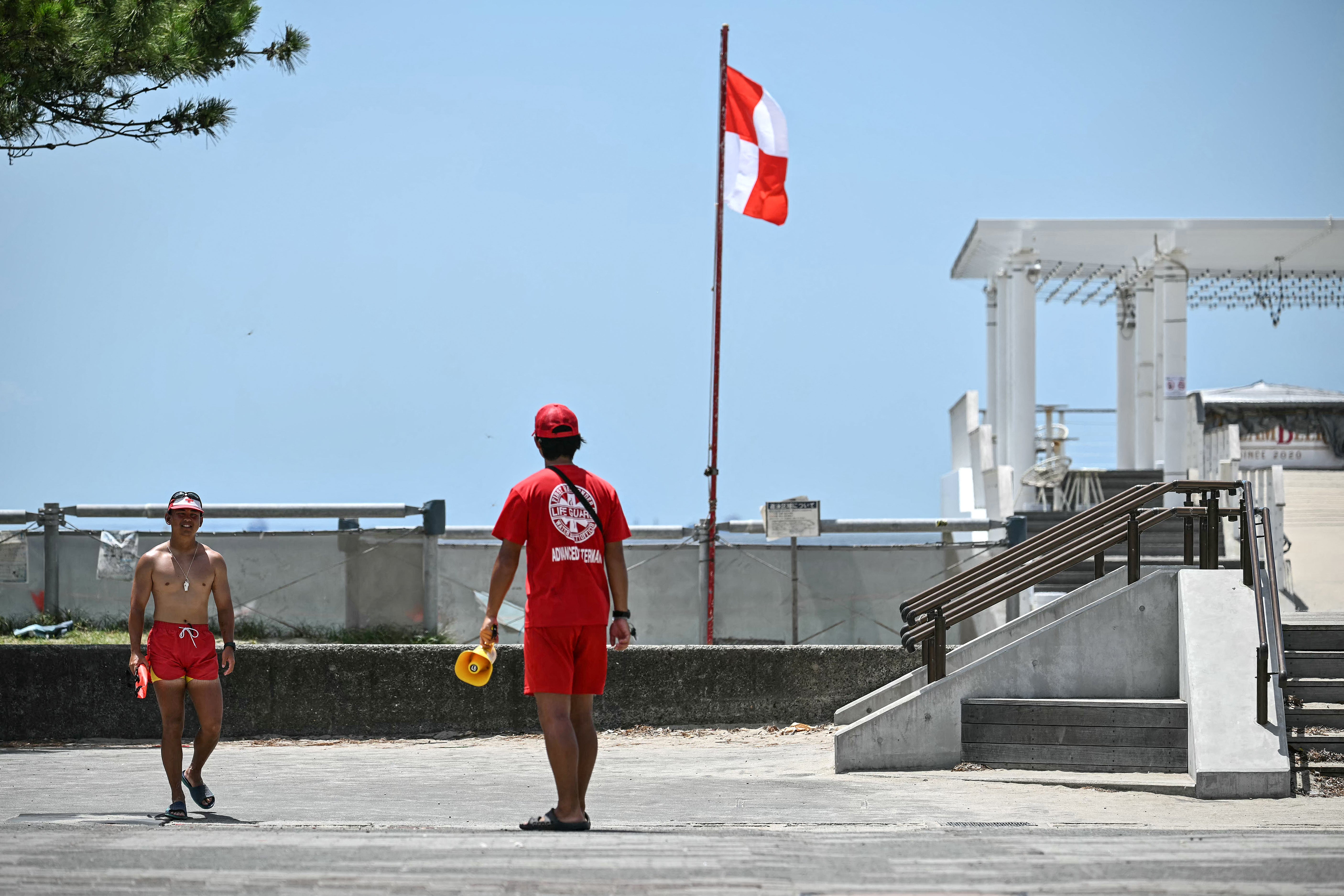 Lifeguards patrol next to a red and white flag used for tsunami warnings