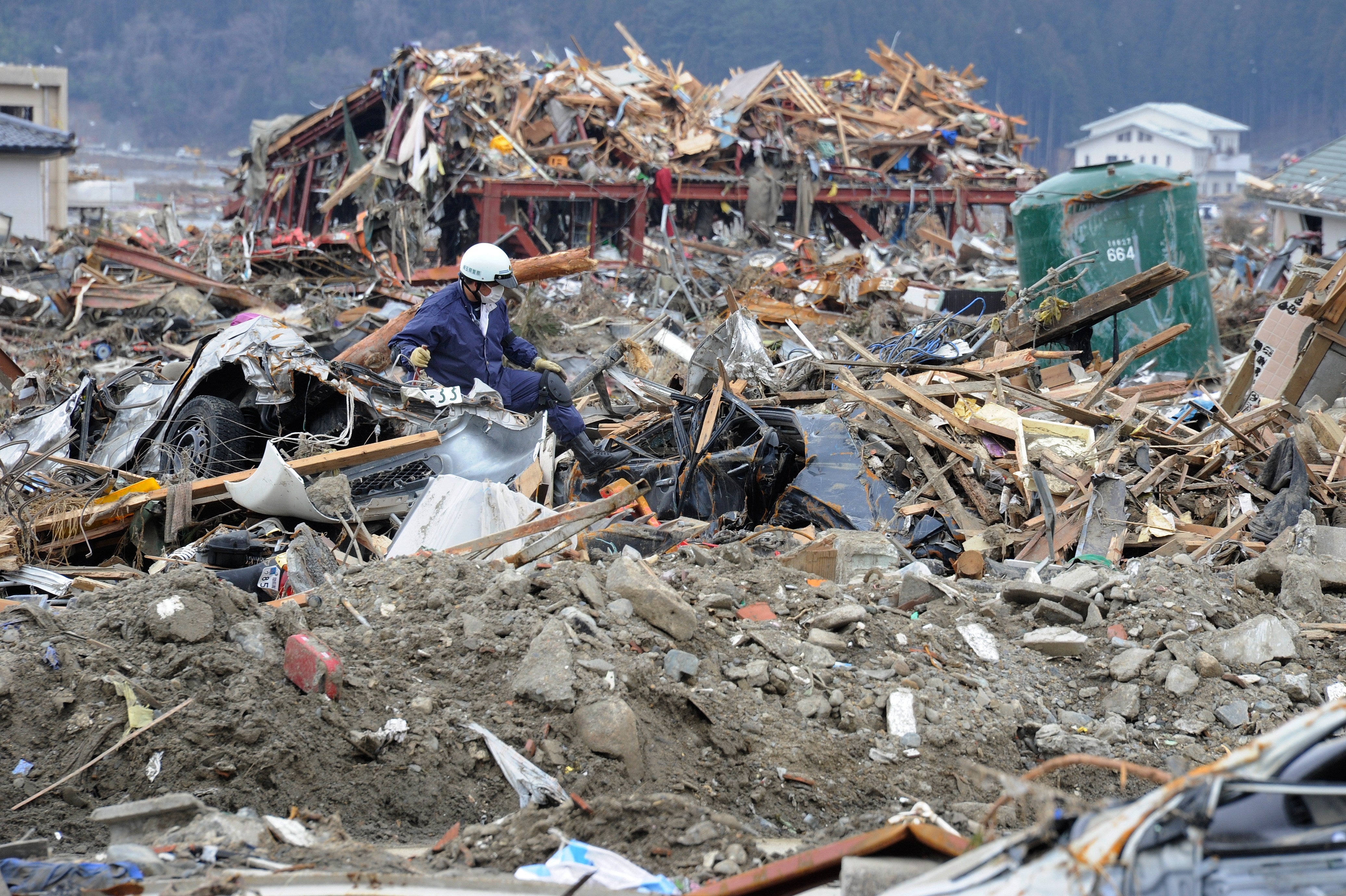 A policeman picks his way through the debris looking for bodies in Rikuzentakata, Iwate prefecture, on March 22, 2011