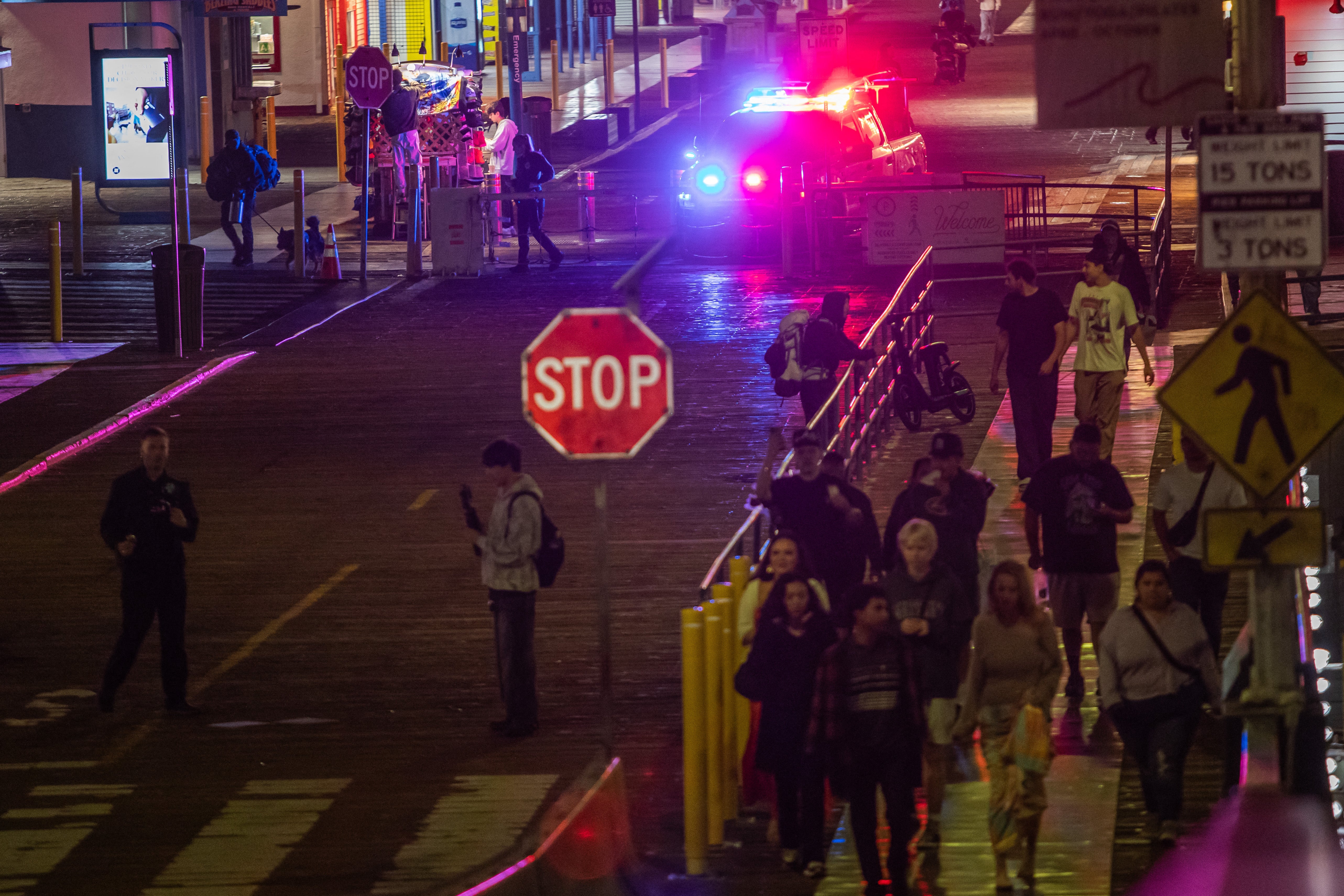 A police officer drives at Santa Monica Pier while warning the public about the regular closure time of the pier amid a tsunami warning