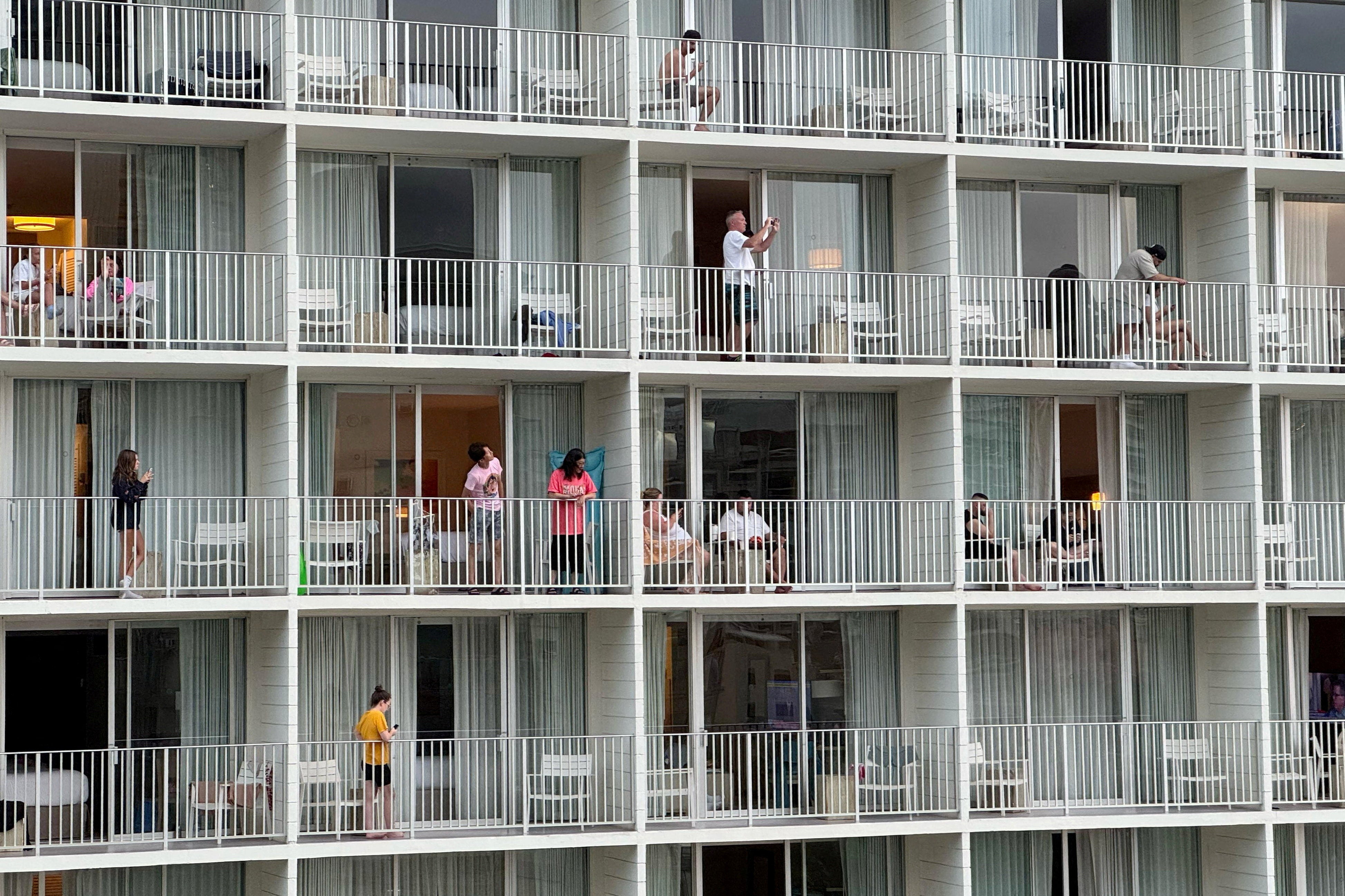 Vacationers stand on balconies at the 'Alohilani Resort looking towards Waikiki Beach after authorities warned of the possibility of a tsunami