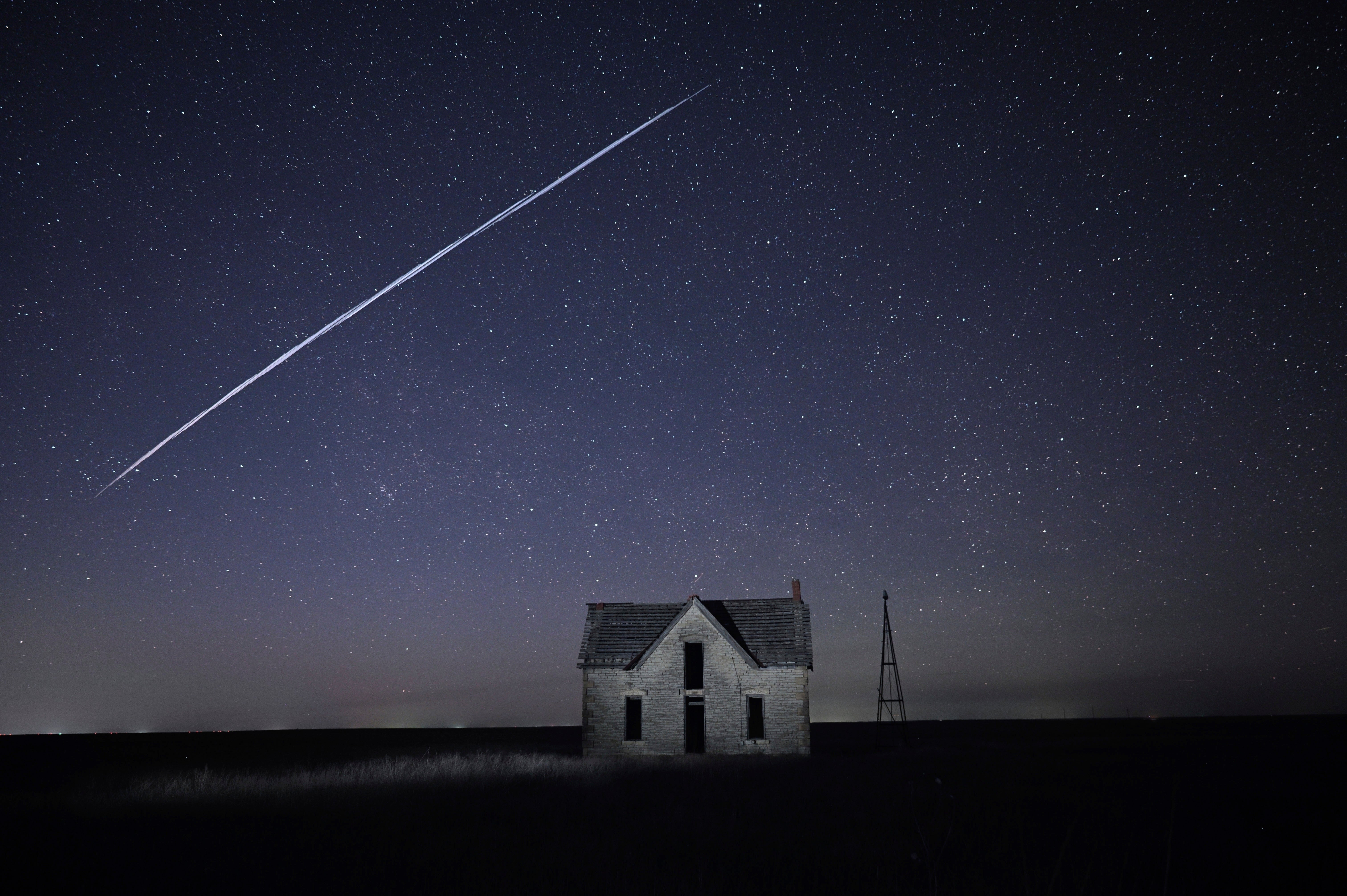 A string of SpaceX StarLink satellites passes over an old stone house near Florence, Kan., on May 6, 2021. (AP Photo/Reed Hoffmann, File)