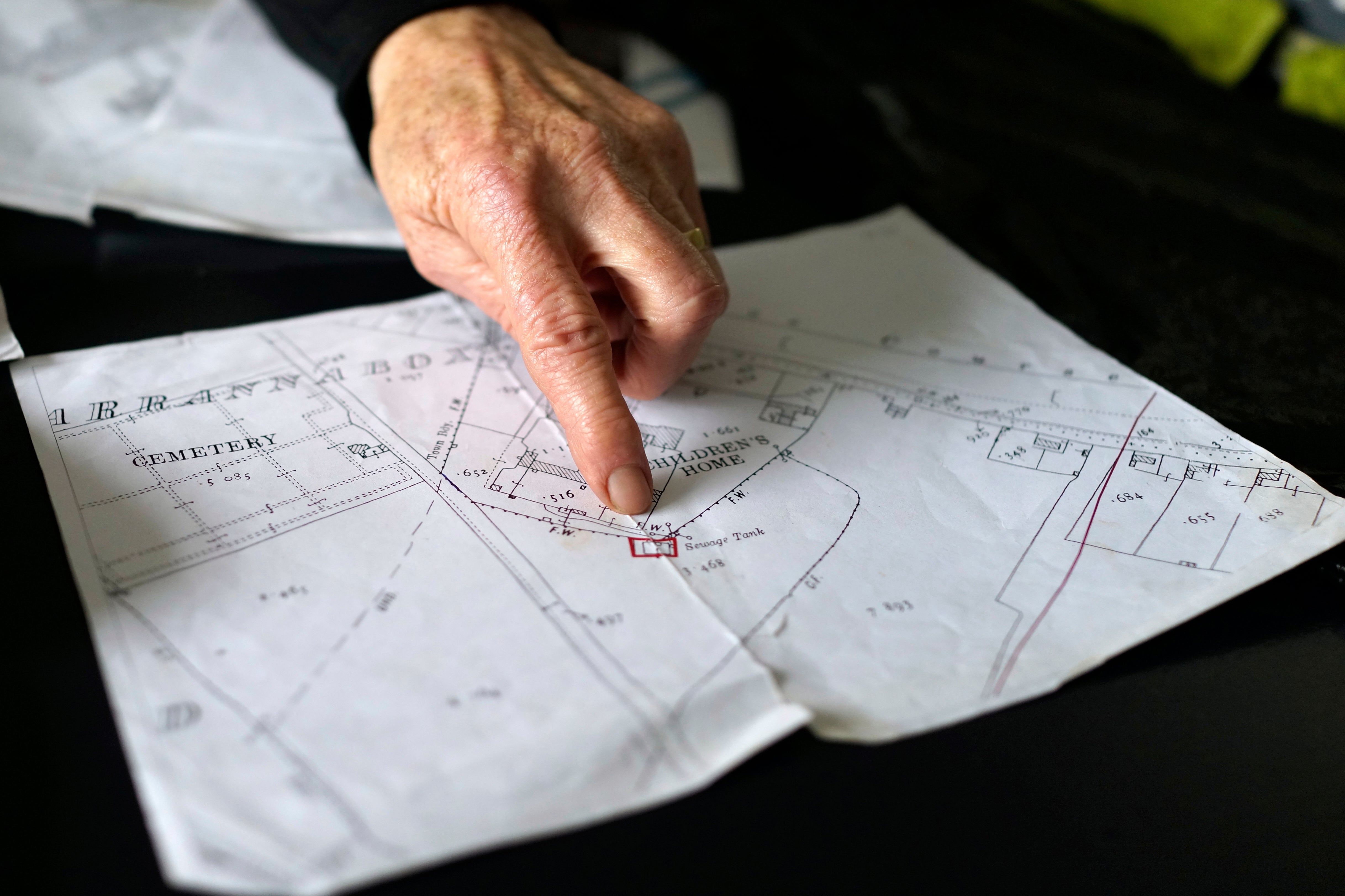 Catherine Corless, who revealed that remains of nearly 800 dead infants from a mother and baby home in Tuam, Ireland, were unaccounted for and likely buried in a mass grave, points on a map at her home outside Tuam on Tuesday, July 8, 2025. (AP Photo/Brian Melley)