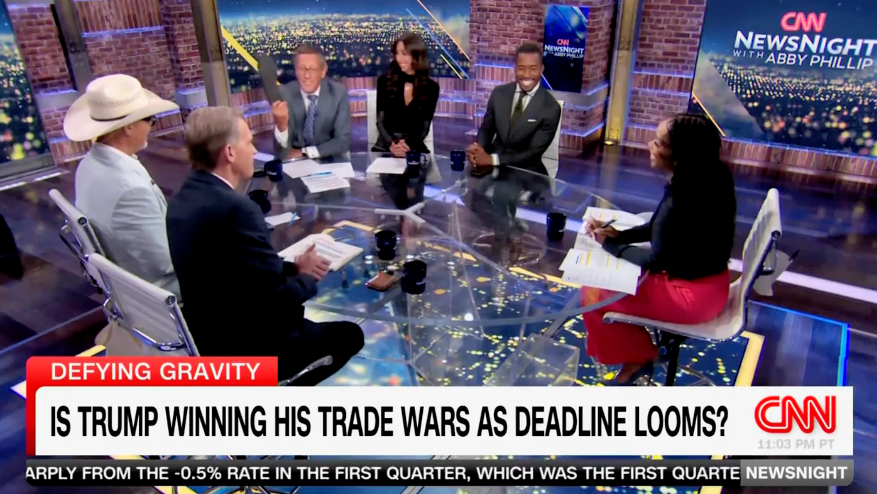 CNN international business correspondent Richard Quest waves his shoe in the air as his fellow panelists watch. Quest previously took his shoe off during an April CNN panel, citing it as an example of a product that will go up in cost under Trump's tariffs