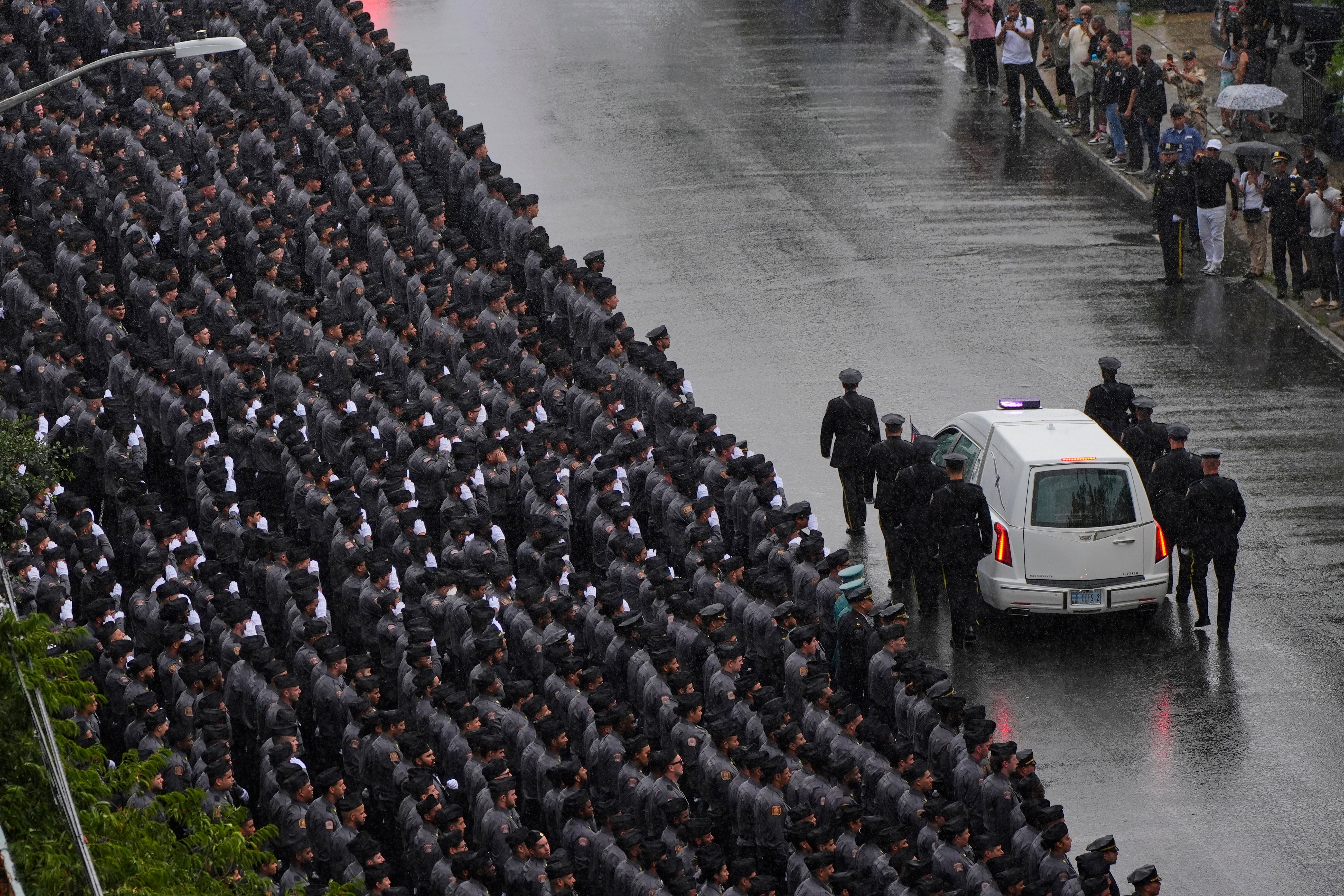 NYPD personnel salute as the hearse carrying the casket of police officer Didarul Islam passes following his funeral