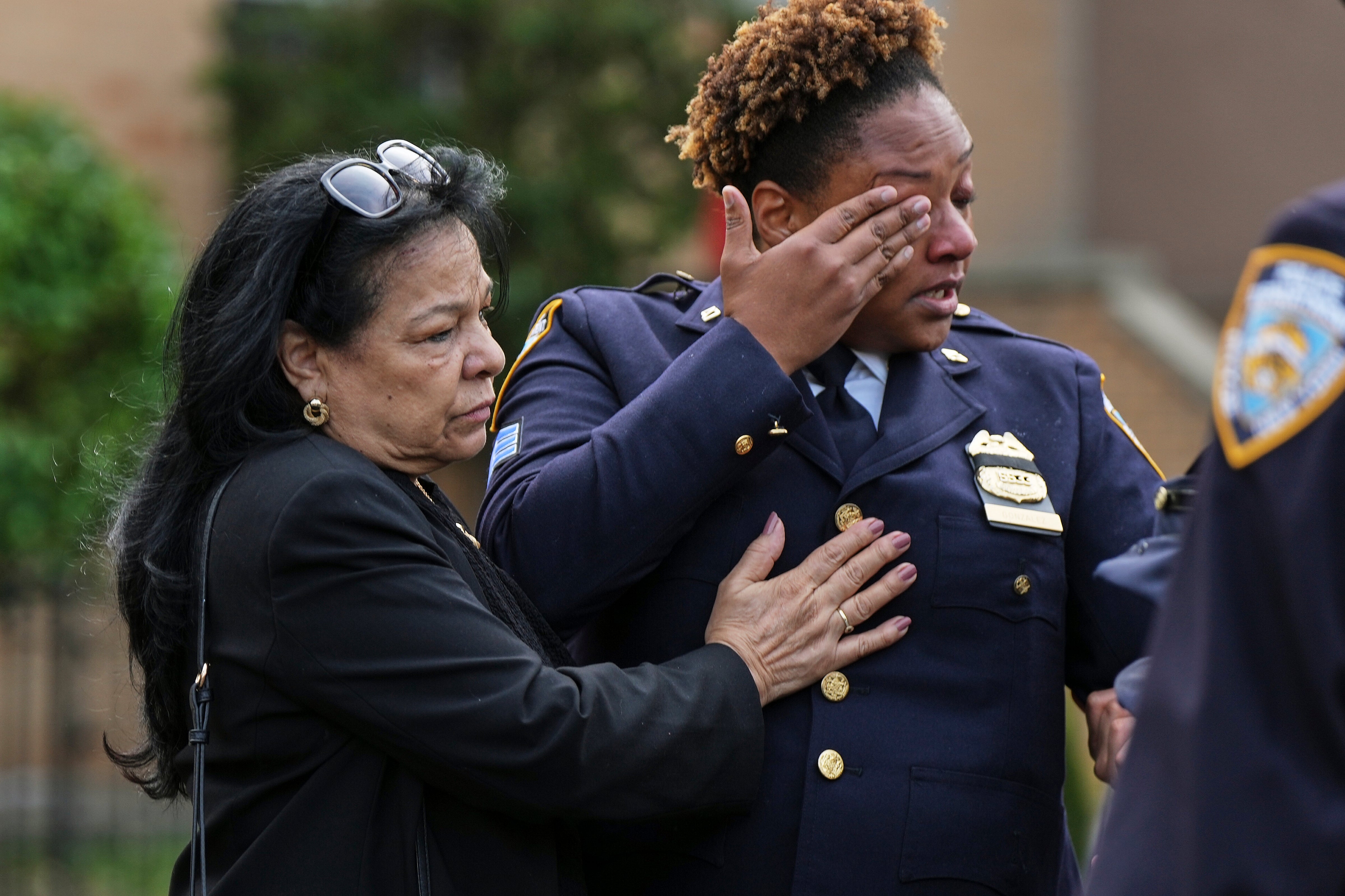 New York Police officer Jackeline Gonzalez, right, reacts as she gathers with other officers outside the Parkchester Jame Masjid mosque for the funeral