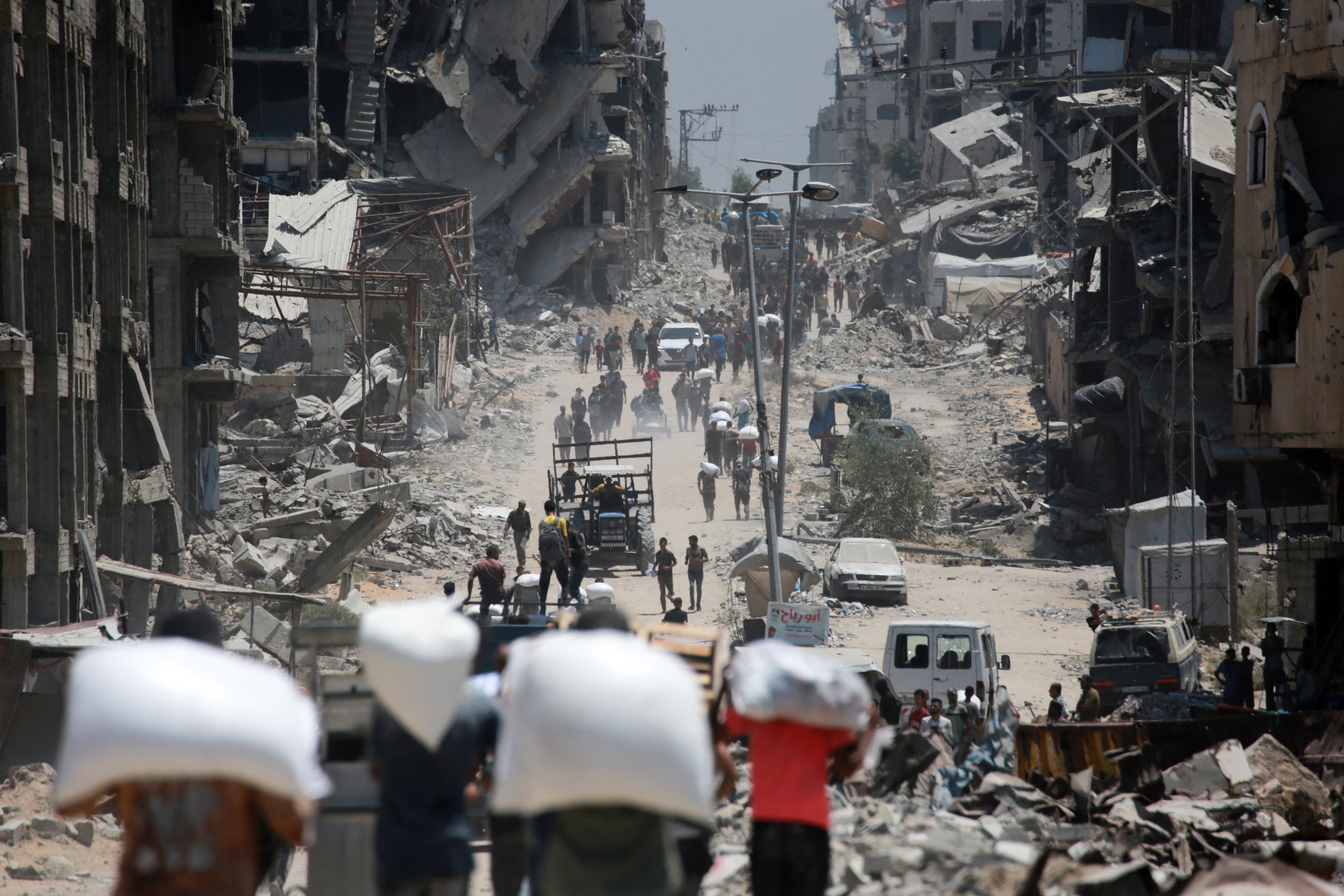 Palestinians carry bags of flour that they obtained from aid trucks which entered Gaza through the Zikim crossing point, in Jabalia in the northern Gaza Strip