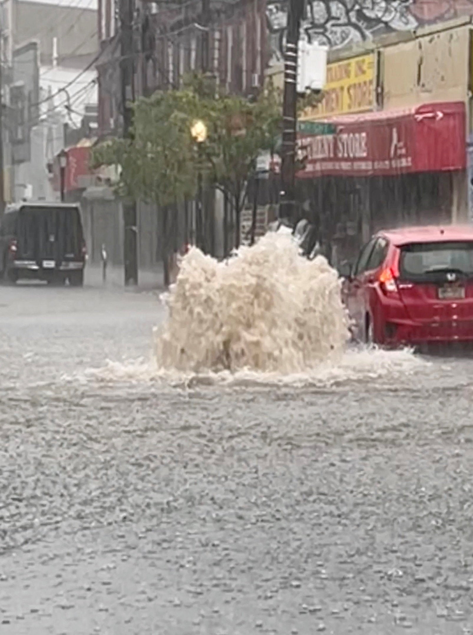 A car drives on a flooded street after heavy downpours in Staten Island, New York on Thursday