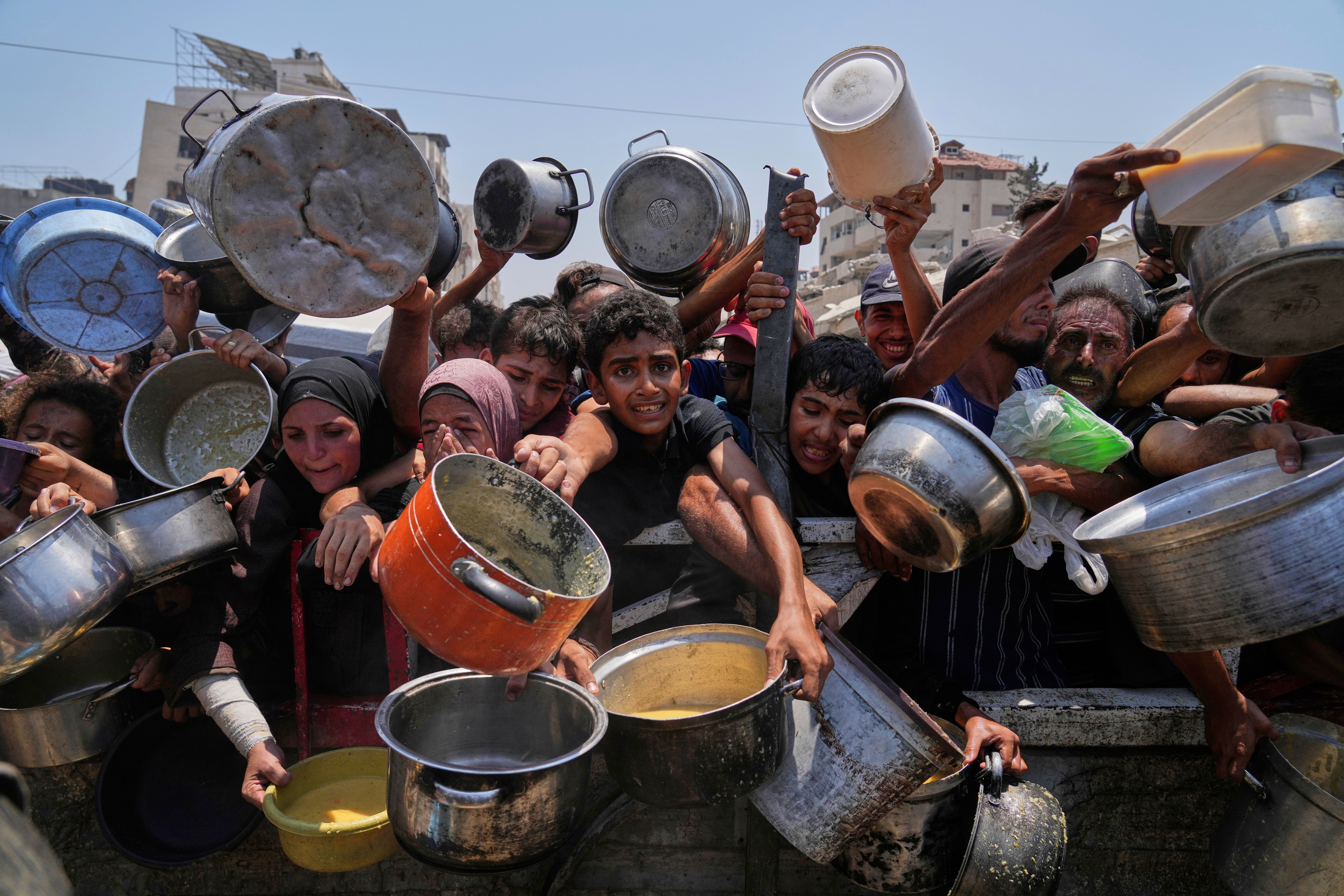 Palestinians struggle to get donated food at a community kitchen in Gaza City