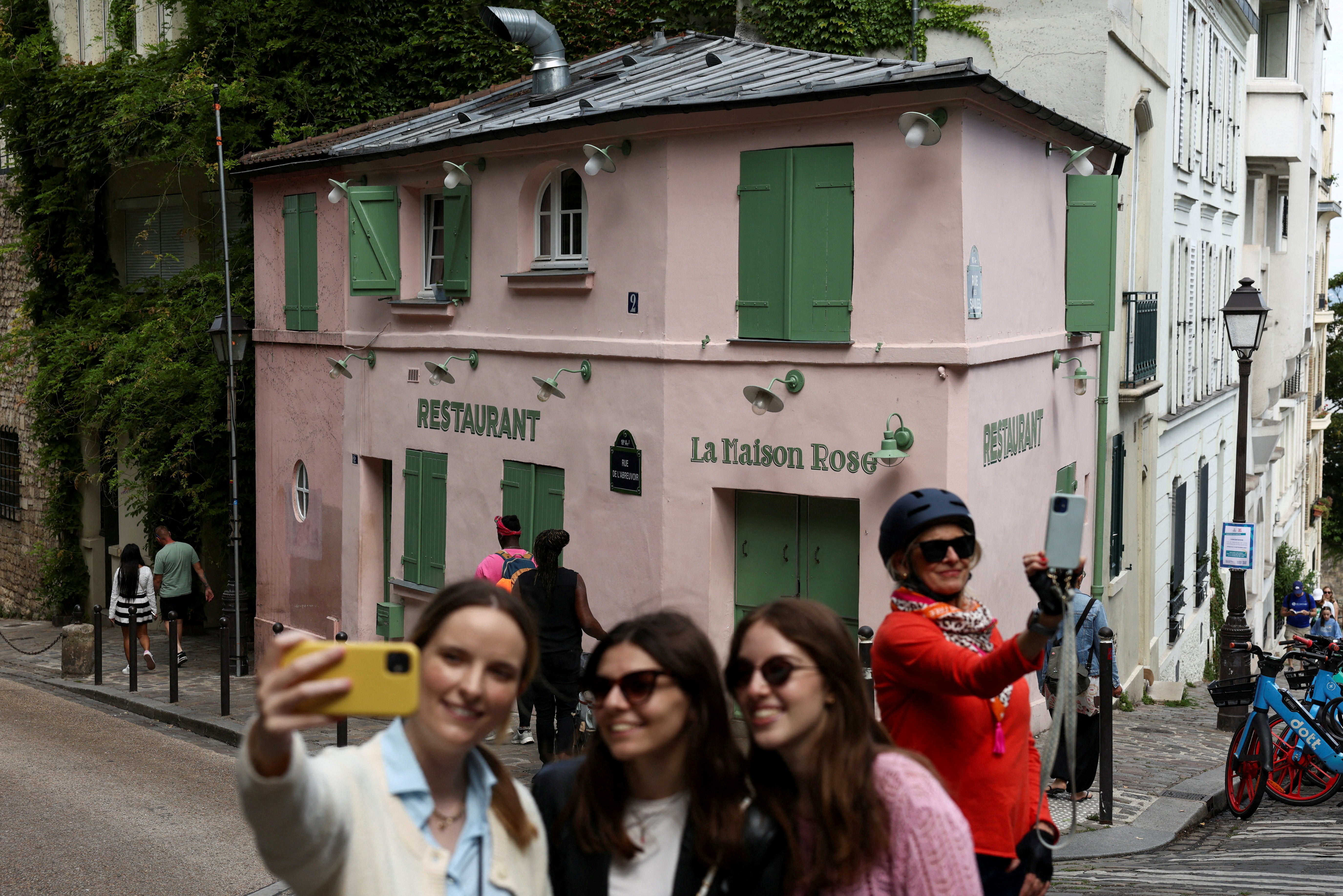 Tourists take photos in front of "La Maison Rose" restaurant in Montmartre, Paris, France, July 29, 2025