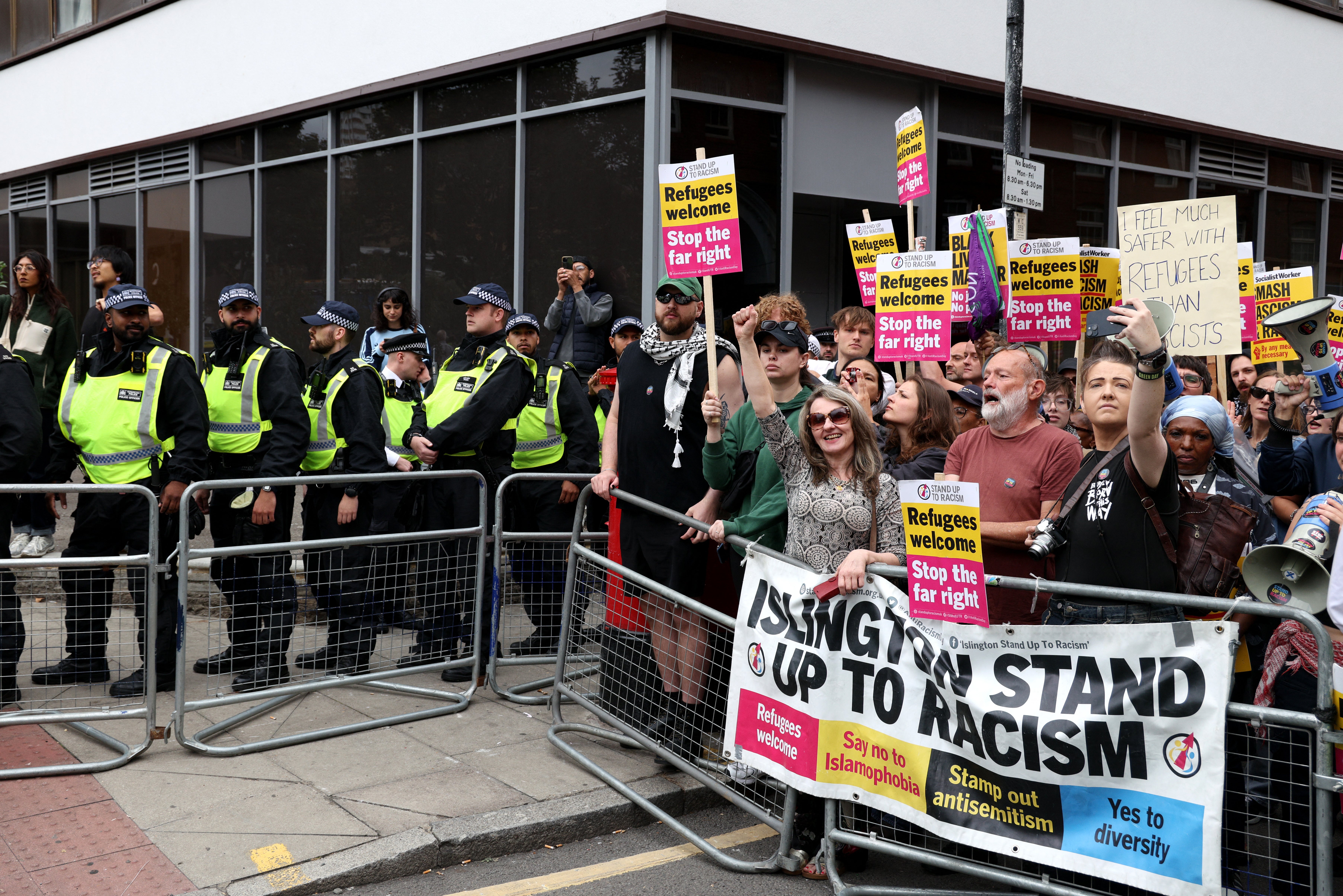 Protestors hold placards during a counterdemonstration organised by ‘Stand Up To Racism’ outside the Thistle City Barbican Hotel, which houses asylum seekers