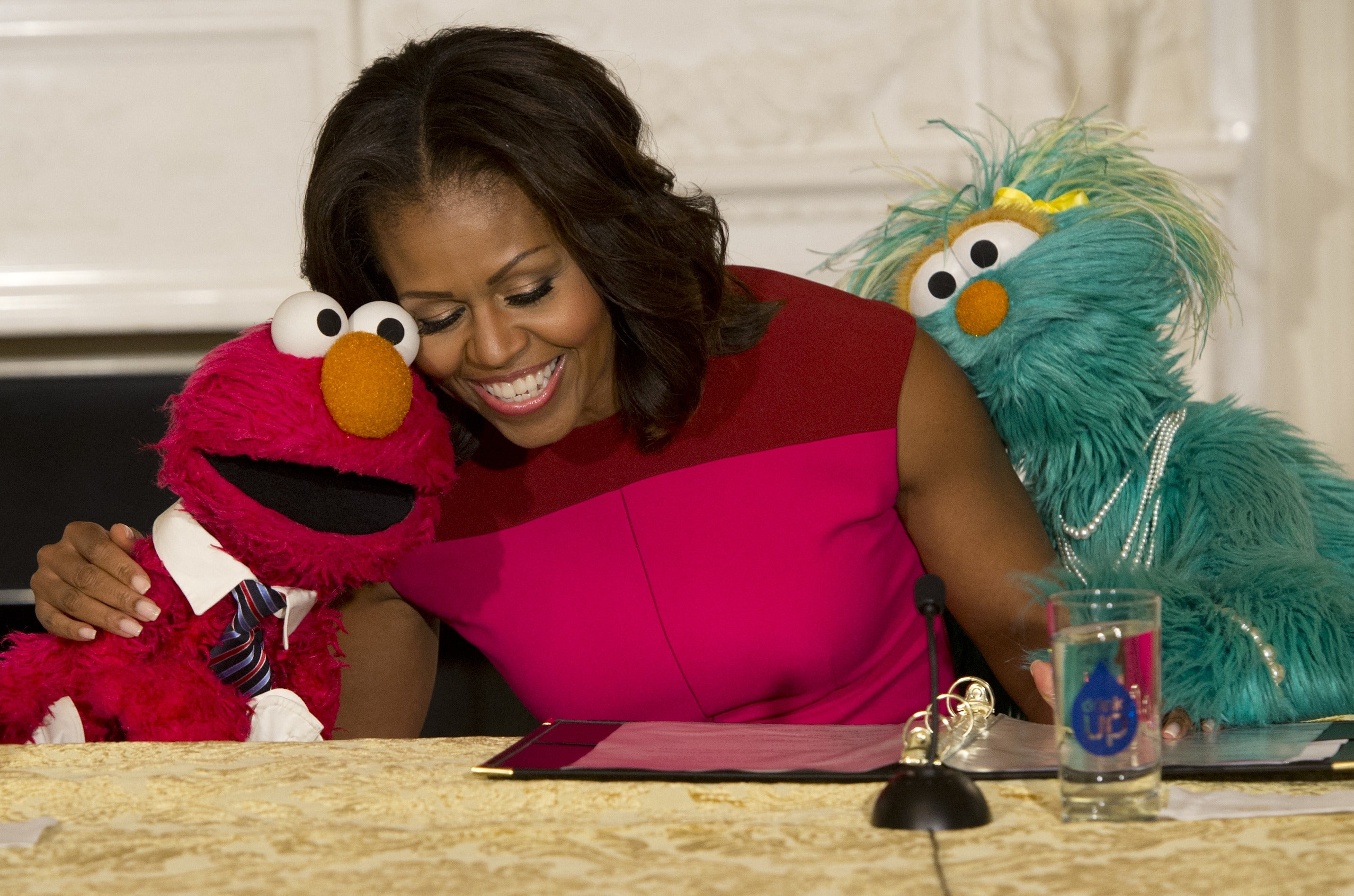 Then-First Lady Michelle Obama embraces Sesame Street characters Elmo and Rosita