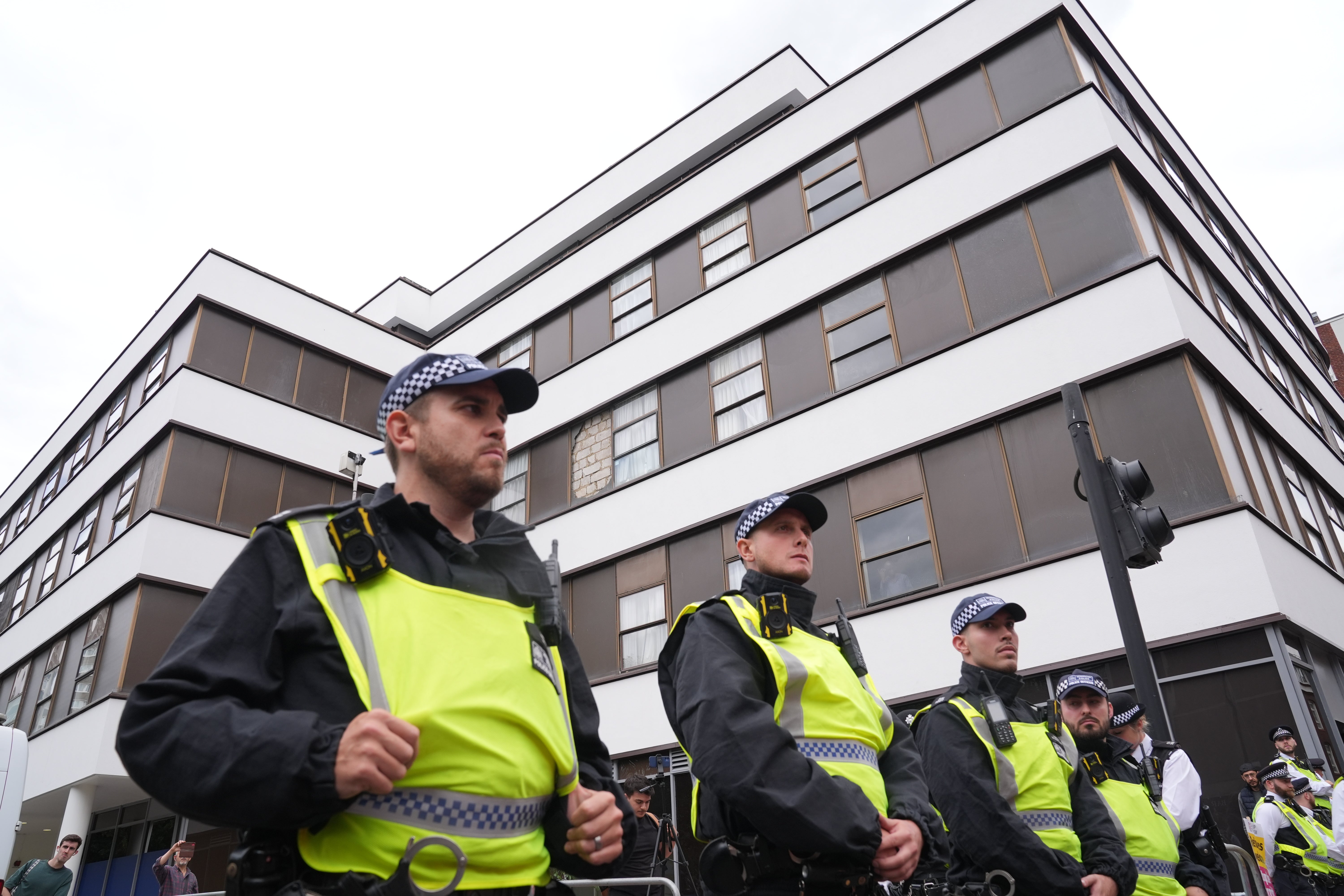 Police officers observe two groups of protesters outside the Thistle City Barbican Hotel in central London (PA)