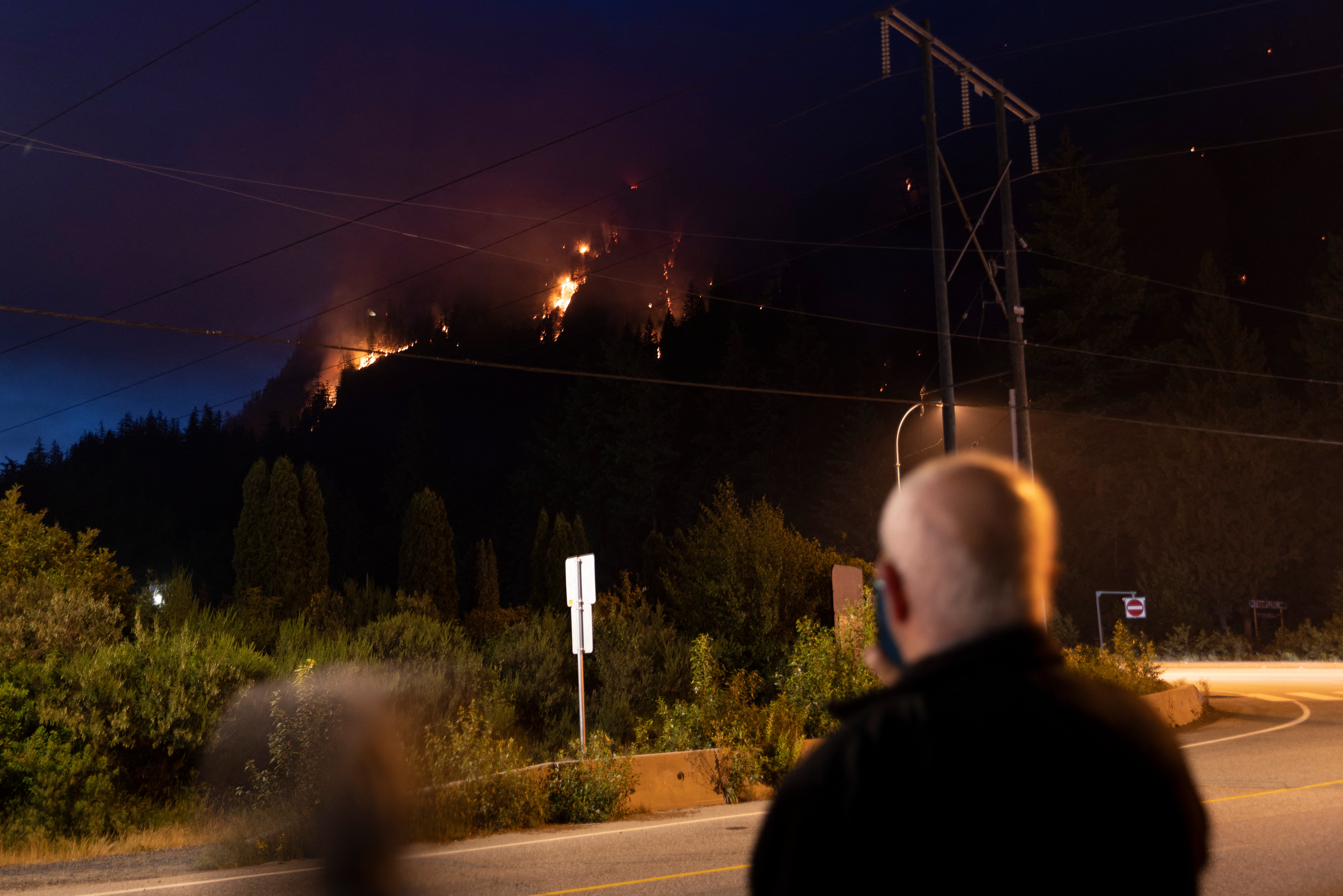 A couple take pictures of a wildfire as its spreads in Squamish, British Columbia, last June. More than 730 wildfires are active throughout Canada