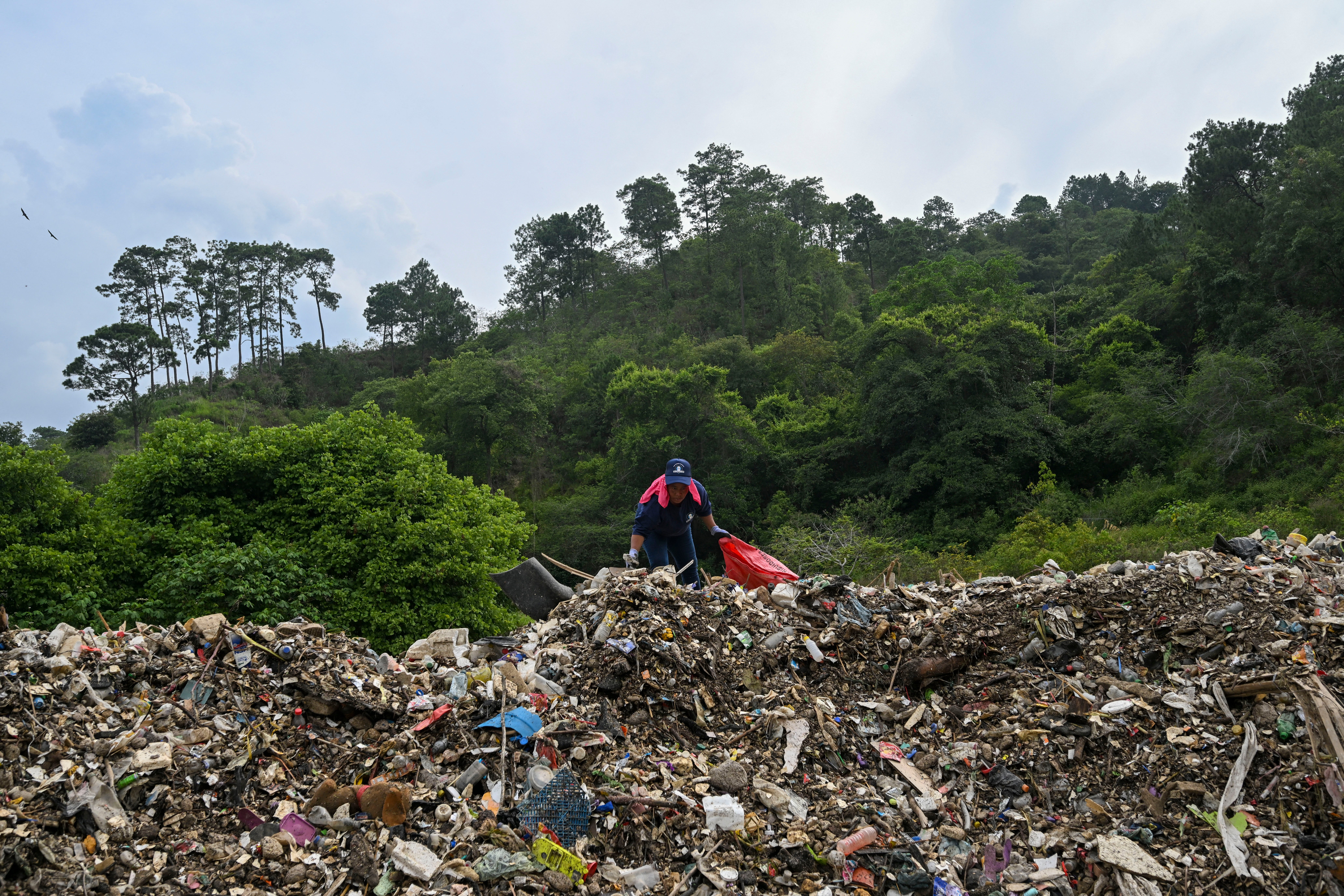 A worker looks for recyclable material amid plastic pollution at Las Vacas River in Chinautla, Guatemala, earlier this summer. A global health and environmental crisis, without mitigation researchers say it could get a lot worse